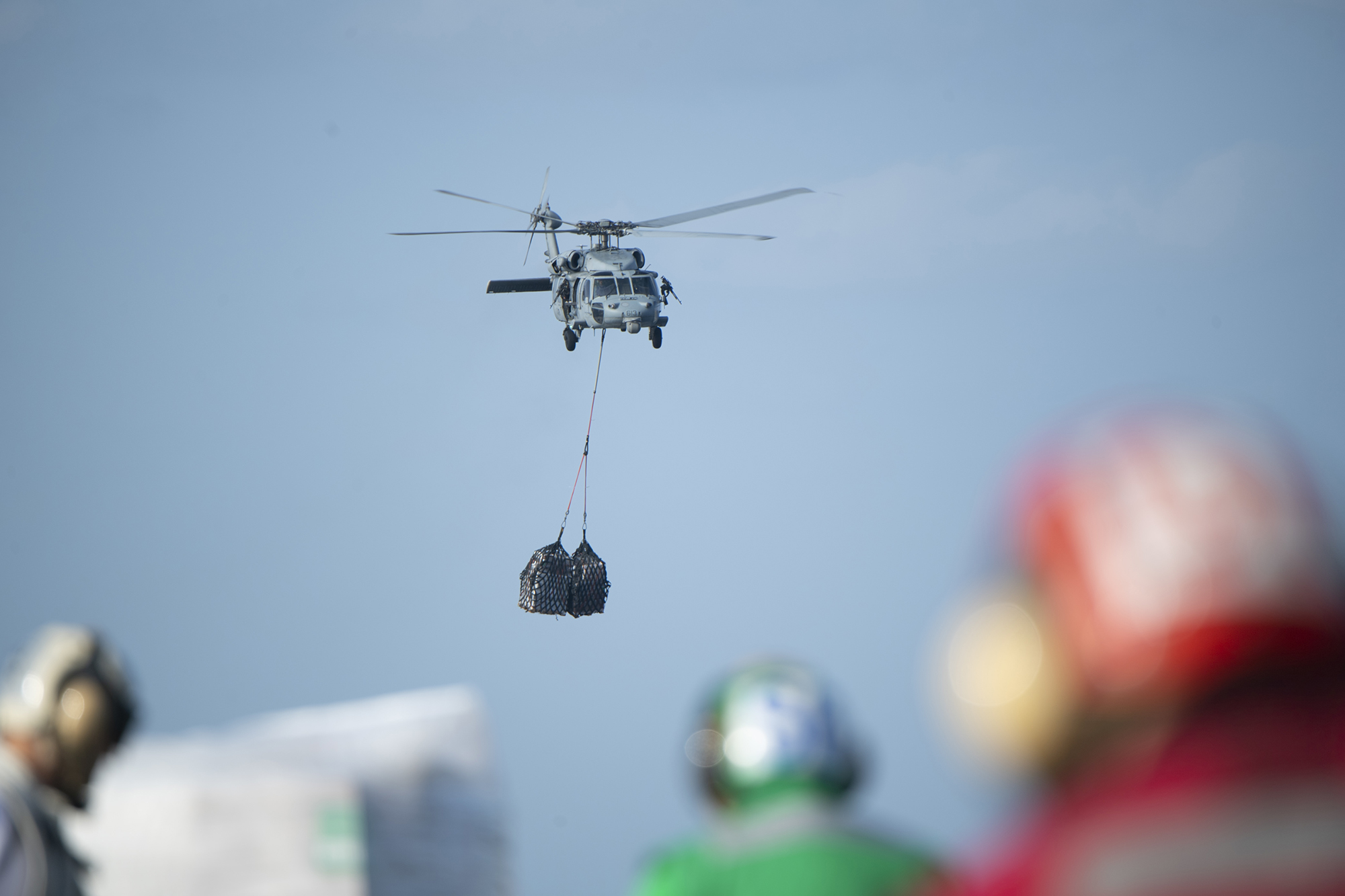 An MH-60S Sea Hawk helicopter transports cargo to the aircraft carrier USS Harry S. Truman (CVN 75) from the USNS Wally Schirra (T-AKE 8) during a replenishment-at-sea in the Arabian Sea on Dec. 21, 2019. (Mass Communication Specialist 2nd Class Jake Carrillo/Navy)