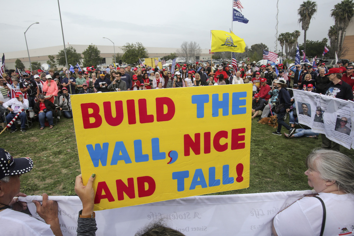 Supporters of President Donald Trump display signs during a rally attended by about 500 people in San Diego, Calif., on March 13, 2018, where he was visiting the nearby border wall protoypes. (Bill Wechter/AFP via Getty Images)