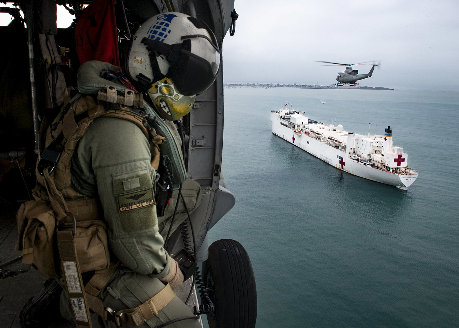 Naval Aircrewman (Helicopter) 1st Class Robert P. McCann flies in an MH-60S Sea Hawk helicopter alongside a Peruvian military Bell 412 on July 21, 2019, over the hospital ship USNS Comfort (T-AH 20). (Mass Communication Specialist 2nd Class Morgan K. Nall/Navy)