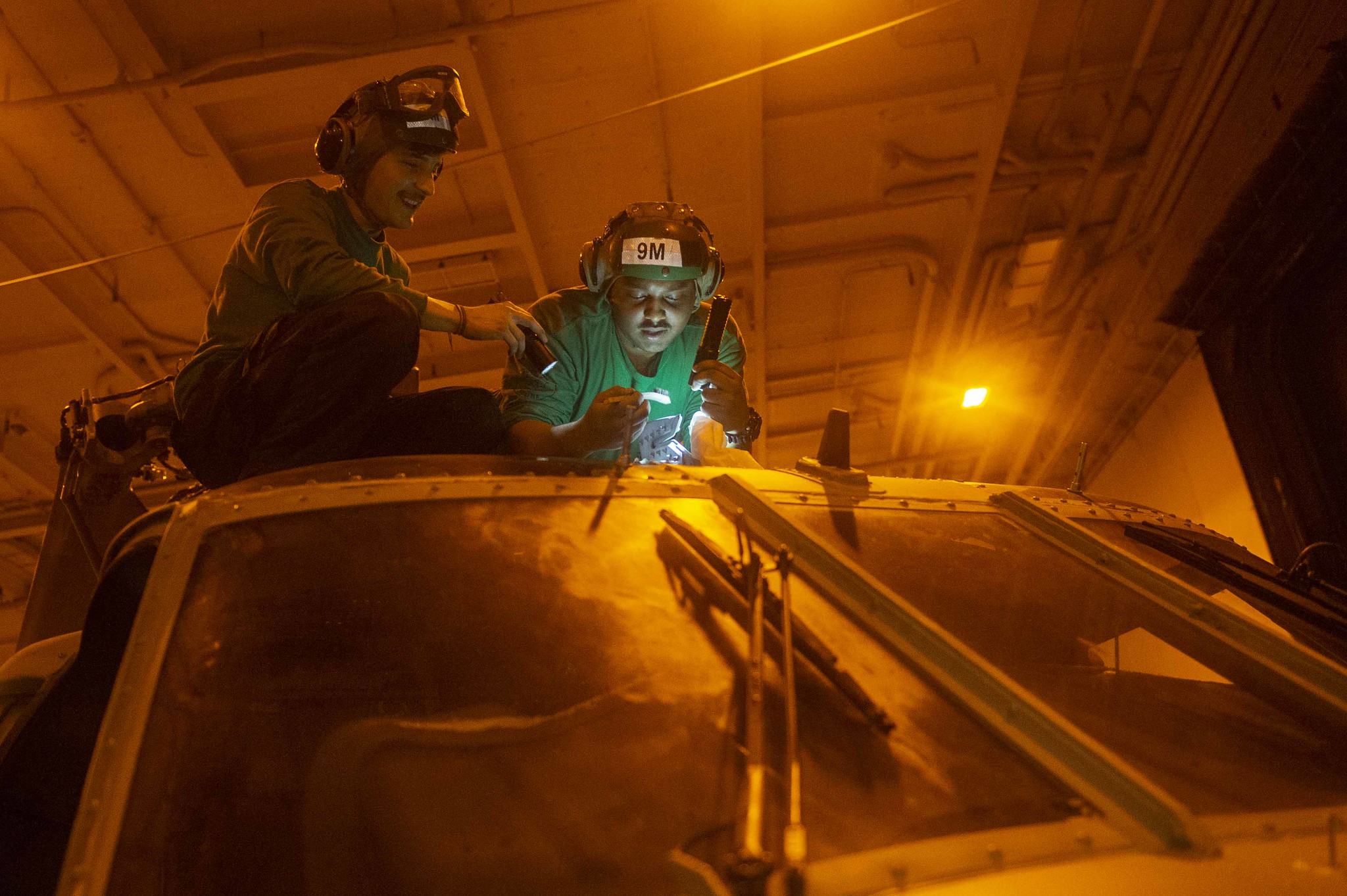 Aviation Structural Mechanic 2nd Class Daniel Rivera and Aviation Structural Mechanic 3rd Class Anthony Morales remove corrosion on the main rotor head of an MH-60S Seahawk helicopter in the hangar bay of the aircraft carrier USS Harry S. Truman (CVN 75) on Jan. 2, 2020, in the Arabian Sea, Jan. 2, 2020. (Mass Communication Specialist 3rd Class Megan Wollam/Navy)