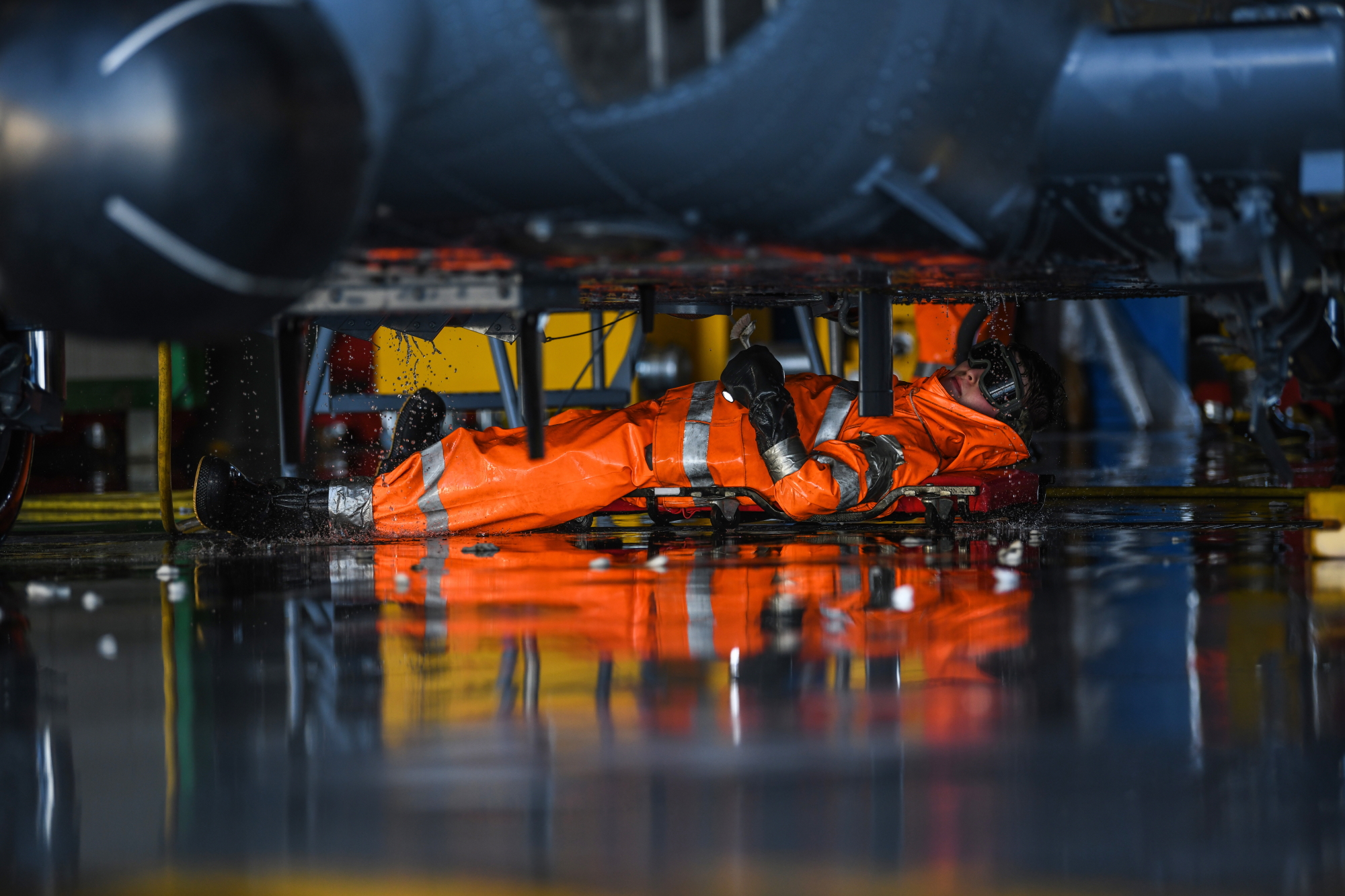 Airman James Eyler, a 31st Aircraft Maintenance Squadron crew chief, washes under an HH-60G Pave Hawk helicopter at Aviano Air Base, Italy, Oct. 22, 2019. (Airman 1st Class Ericka A. Woolever/Air Force)