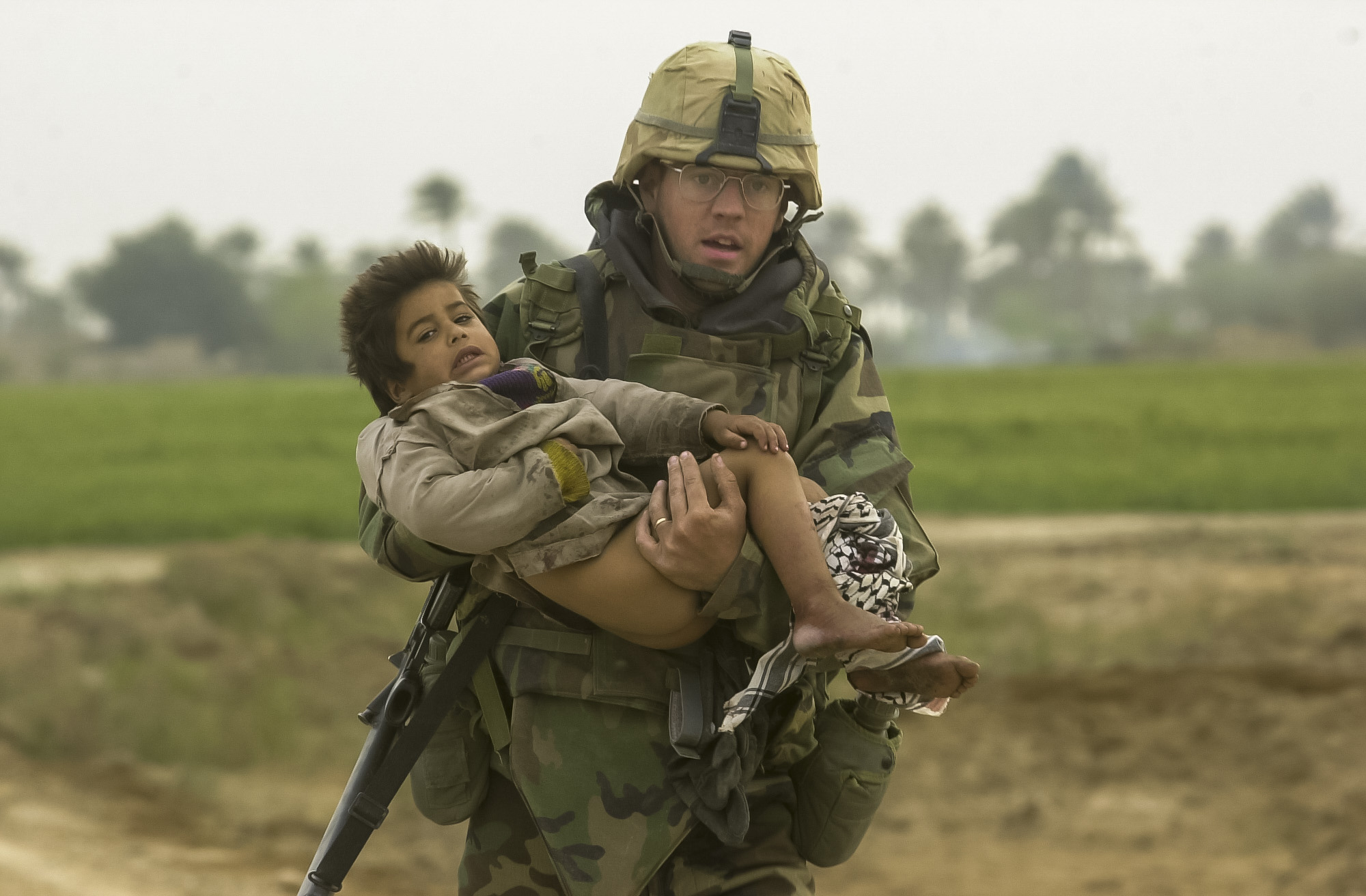 PFC Joseph DeWitt, 26, from Suffock County, Ny, runs while carrying a young Iraqi boy who was injured during a heavy batle between the U.S. Army's 7th Cavalry Regiment and Iraqi forces near the village of Al Faysaliyah, Iraq. The Cavalry spent the entire night fighting through the areas and within the city of Al Faysaliyah. The U.S. took no casualties while the Iraqis took estimated 150 casualties inflicted by the Cavalry on March 25, 2003. (Warren Zinn/Army Times)