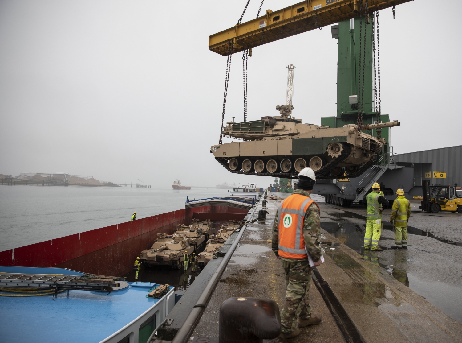 Army Reserve Cpl. Dustin Jobe supervises as an M1A2 Abram Tank is raised over the pier ledge at the Port of Vlissingen, Netherlands, on Oct. 12, 2019. (Sgt. Kyle Larsen/Army)