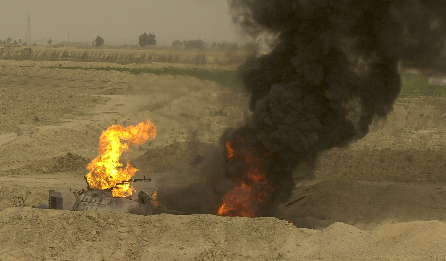 The remains of an Iraqi tank burns in a ditch Friday afternoon in southern iraq on March 23, 2003 near a USMC artillery fighting position. (Jud Mccrehin/Marine Corps Times