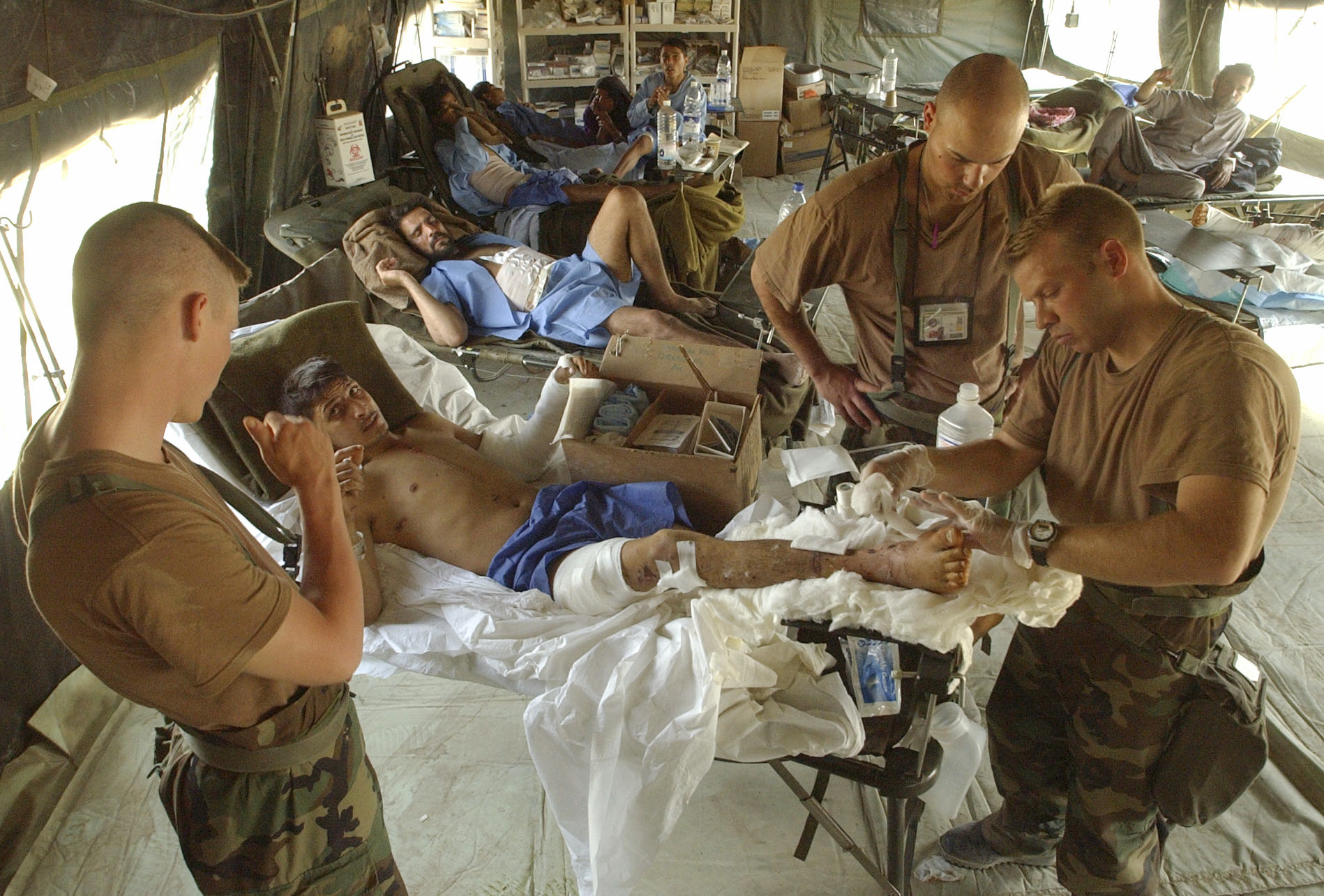 Medical personel of the U.S. Army 86th Combat Support Hospital located at Tallil air base in Southern Iraq, change the dressings on a wounded Iraqi civilian. Spec. Brian Herndon,left, from Carlsbad, NM, 1st Lt. Dave Allen, middle right, from Columbus OH, and Spec. James Shead, right, from Austin Texas care for the wounded. (Alan Lessig/Army Times)