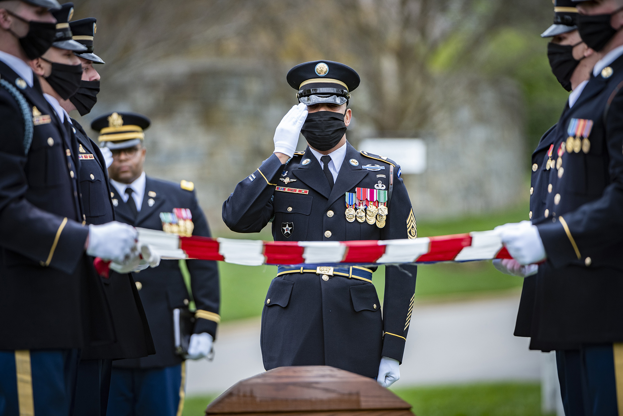 A soldier assigned to The Old Guard renders honors shortly after the chaplain provided his blessing April 14, 2020, during the funeral for retired Army Command Sgt. Maj. Robert M. Belch in Arlington National Cemetery, Arlington, Va. Given current health protection guidance from the secretary of defense, Old Guard soldiers wear face coverings to mitigate the spread of COVID-19 while executing the memorial affairs mission. (Elizabeth Fraser/Army)