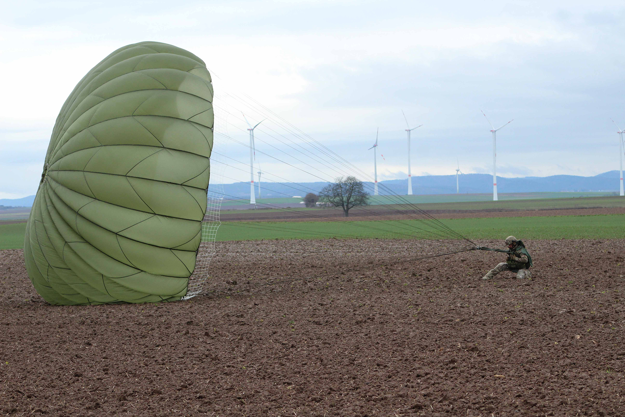 A U.S. Army paratrooper lands at Alzey drop zone Dec. 18, 2019, after jumping off a C-160 during Operation Toy Drop 2019, at Alzey, Germany. (Staff Sgt. Sinthia Rosario/Army)