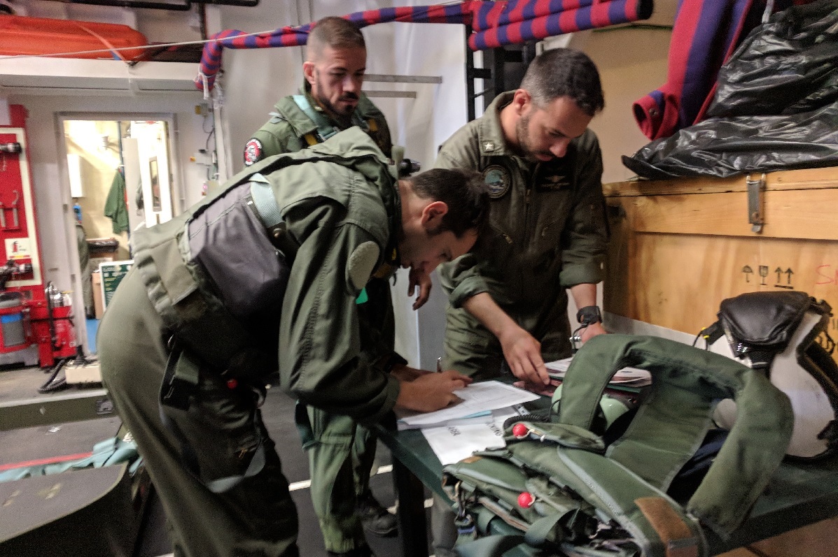 The Italian FREMM Alpino's air boss reviews the preflight checklist, with the aircrew looking on. (David B. Larter/Staff)