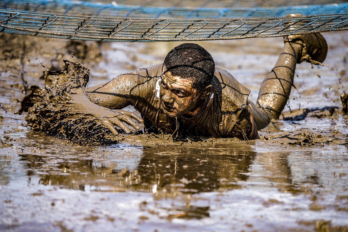 A participant of the 7th annual Rugged Terrain Obstacle Run low crawls through mud April 6, 2019, in the Grafenwoehr Training Area, Germany. (Sgt. Christopher Stewart/Army)