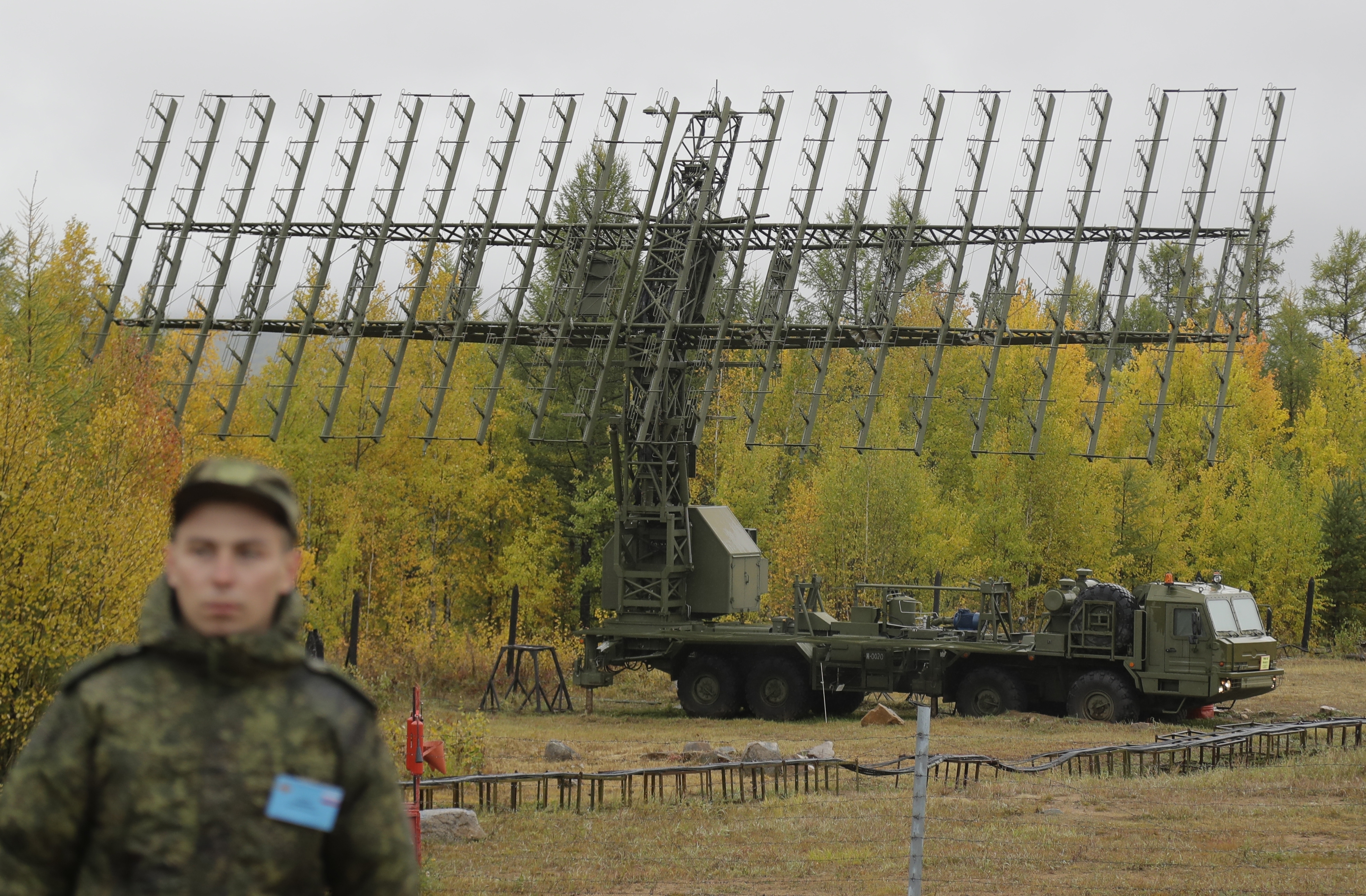 A Russian soldier stands in front of a Nebo-M radar deployed in a forest, during a military exercises on training ground 