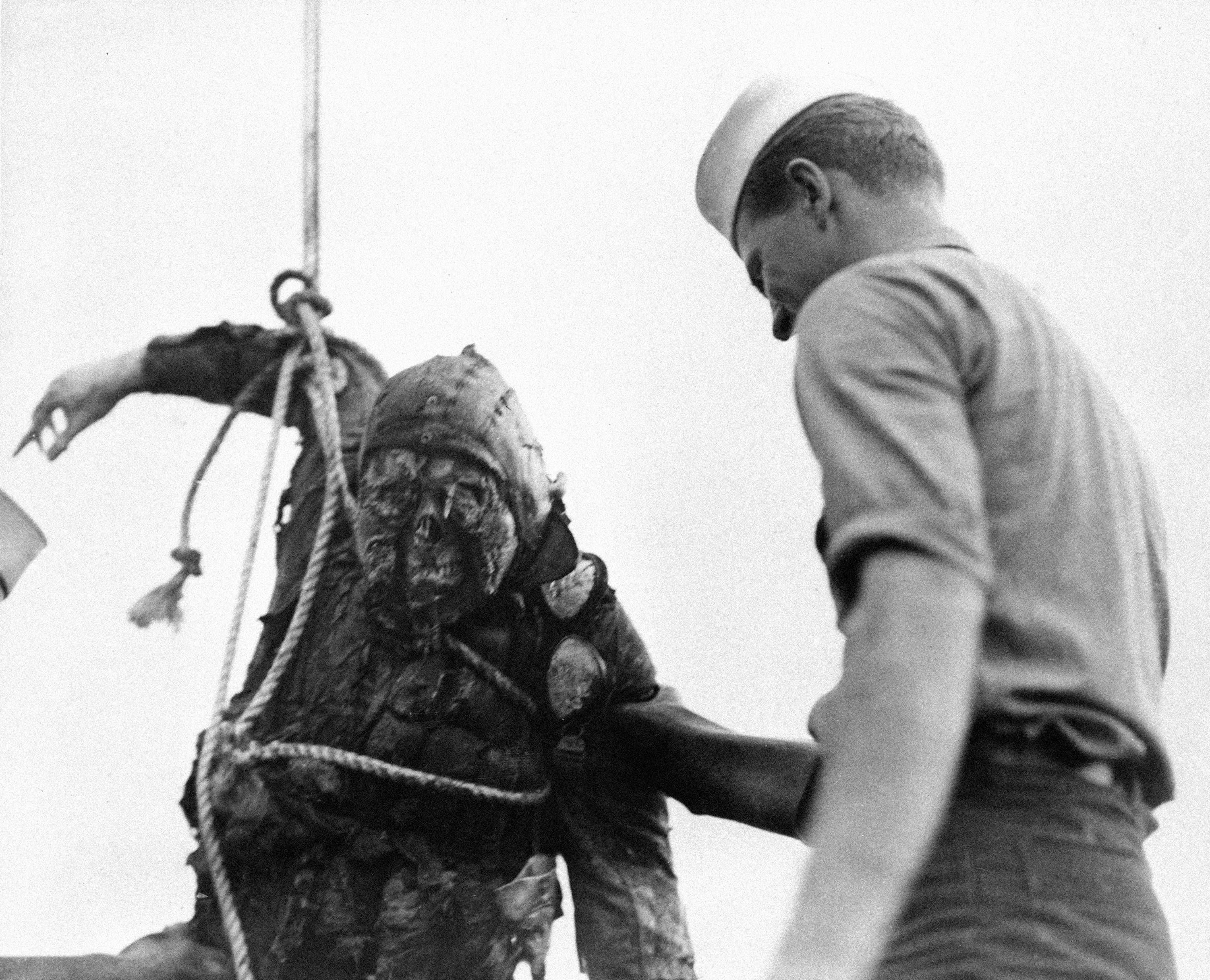 An American Seaman looks at the charred corpse of a Japanese flier brought up from the bottom of Pearl Harbor where he crashed with his burning plane during the Japanese attack on Dec. 7, 1941 in Hawaii. (AP Photo)