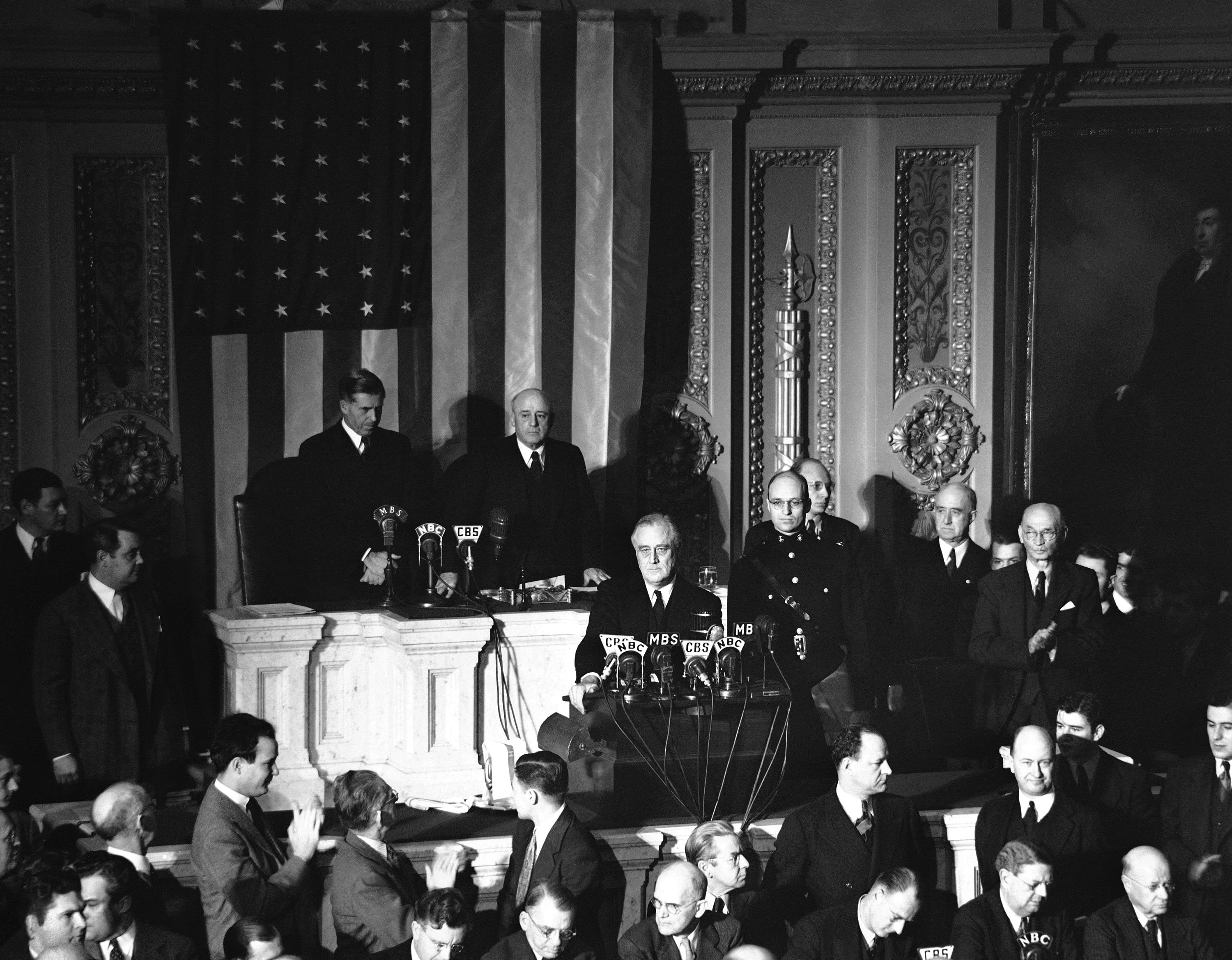 Declaring Japan guilty of a dastardly unprovoked attack, President Franklin D. Roosevelt asked Congress to declare war, Dec. 8, 1941. Listening are Vice President Henry Wallace, left, and House Speaker Sam Rayburn. (AP Photo)