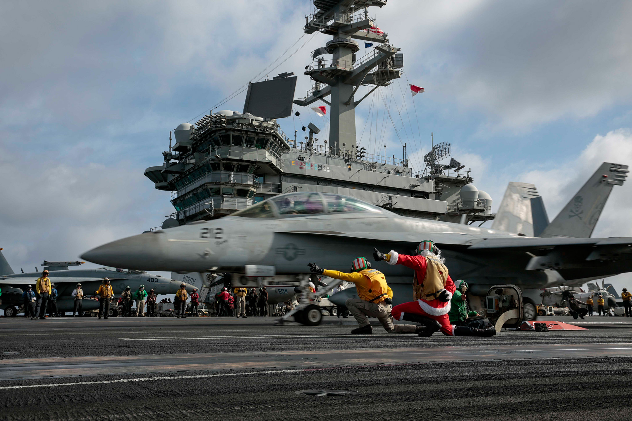 A sailor dressed as Santa Claus directs the launch of an F/A-18F Super Hornet on Dec. 24, 2019, on the flight deck of the aircraft carrier USS Abraham Lincoln (CVN 72) in the South China Sea. (Mass Communication Specialist 3rd Class Michael Singley/Navy)