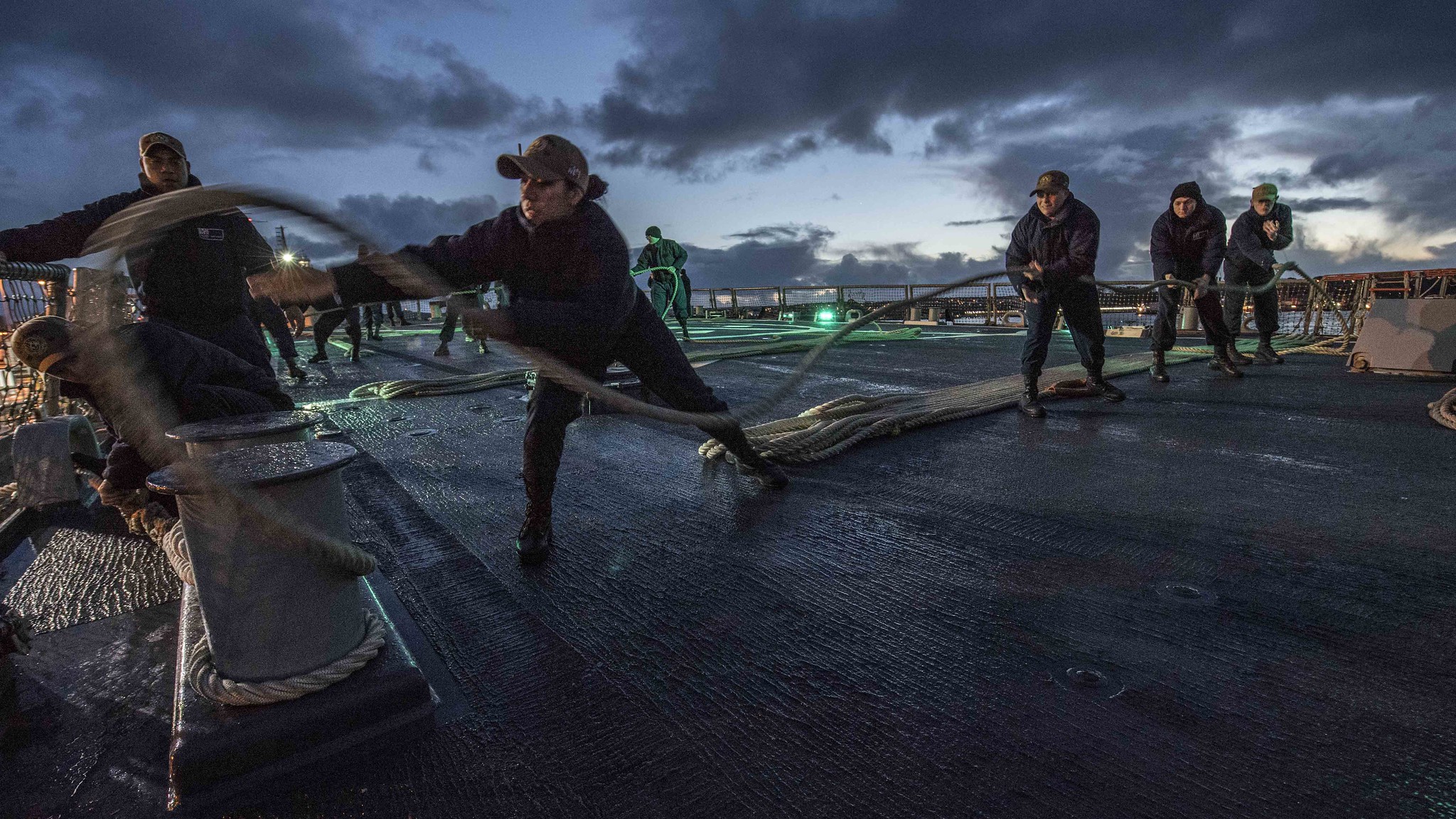 Sonar Technician (Surface) 2nd Class Vanessa Diaz, middle, throws a slacked mooring line around a set of bits during a sea and anchor evolution aboard the Arleigh Burke-class guided-missile destroyer USS Carney (DDG 64), Dec. 11, 2019, in Plymouth, England. (Mass Communication Specialist 1st Class Fred Gray IV/Navy)