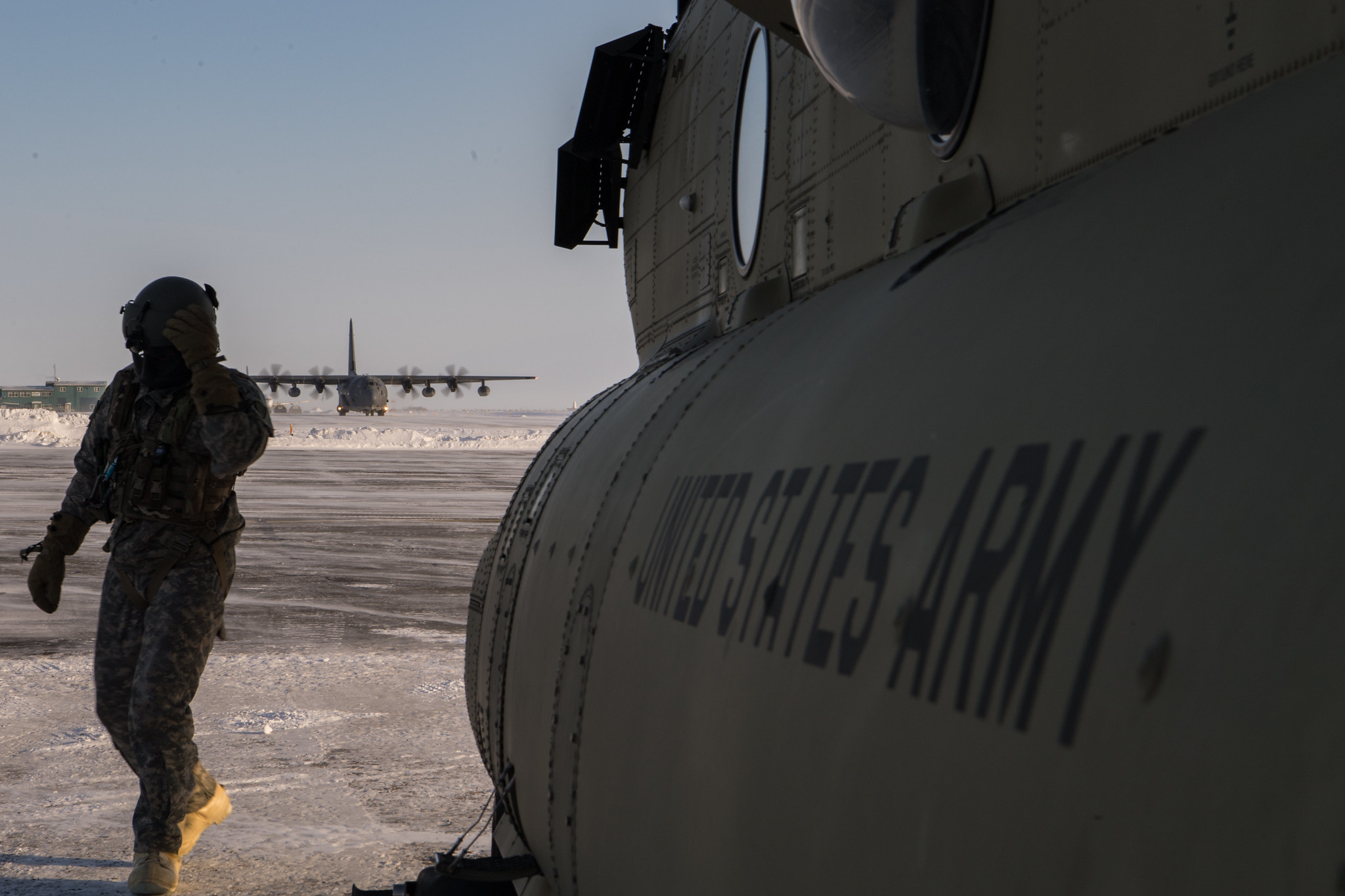 Army Sgt. Lucas Bartel exits the flightline after the completion of a tail-to-tail exchange of cargo and personnel from a CH-47 Chinook helicopter and an HC-130J Combat King II near Deadhorse, Alaska, in support of exercise Arctic Eagle 2020, Feb. 28. (Tech. Sgt. Amy Picard/Air Force)
