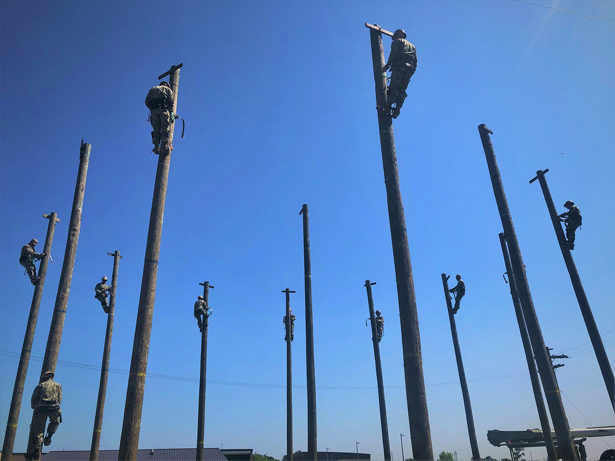 Seabees attending Construction Electrician Core “C” School Pipeline training at Naval Construction Training Center Gulfport on May 20, 2019, advance their skills with wooden power pole utility work during a three-week power distribution systems and line vehicles course in Mississippi. (Chief Construction Electrician Lace Johnson/Navy)