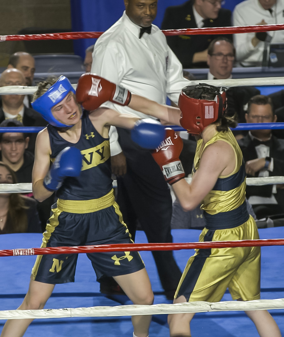 Lisa Kilmer (in gold) throws a punch at Ally Annick (in blue) in the 132 lb weight class bout during the United States Naval Academy's 77th Brigade Boxing Championships held on Feb. 23, 2018. (Alan Lessig/Staff)