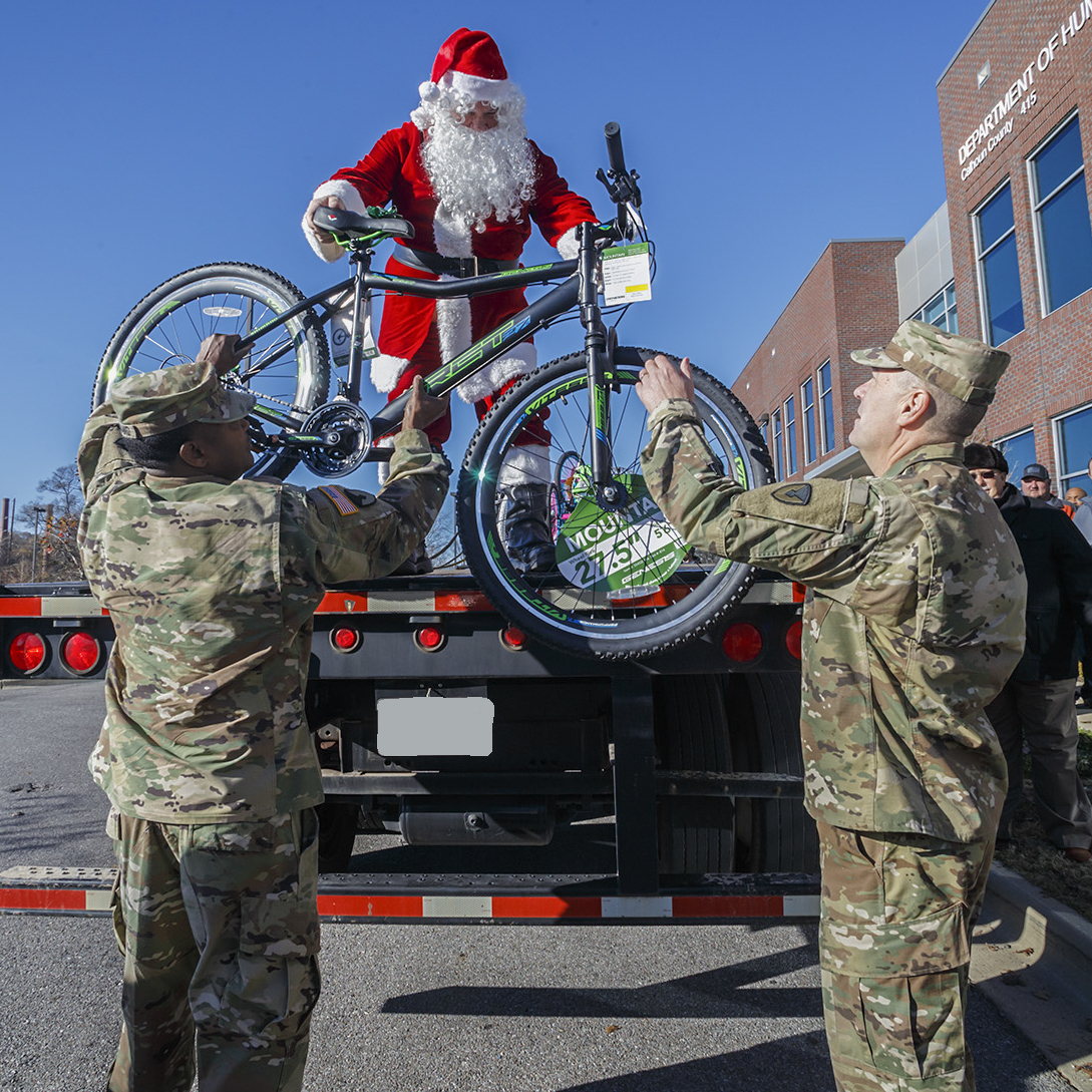 Santa hands a bike to Anniston Army Depot Sgt. Maj. Ronald Ferdinand and Tank, Automotive and Armaments Command Chaplain Lt. Col. David Snyder at the Calhoun County Department of Human Resources. The depot’s 2017 Christmas Cheer program culminated Dec. 10, 2017, with the delivery of three truckloads of gifts and bicycles to the DHR office in Anniston. (Jeffrey Cleghorn/Army)