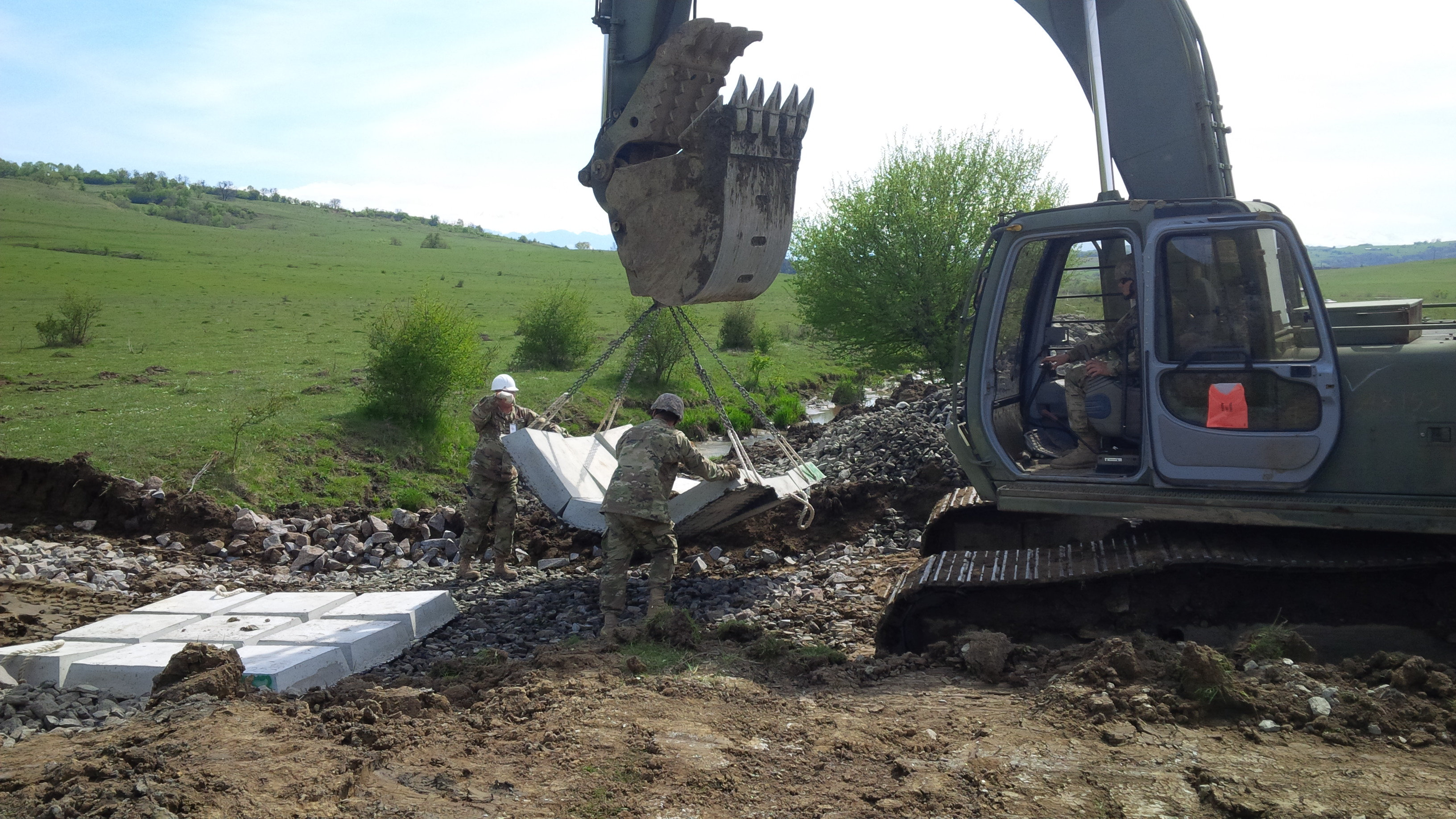 An excavator is used to place concrete mattresses on a low-water crossing being built for the Romanians so their field artillery can reach an area for setup. (Jen Judson/Staff)