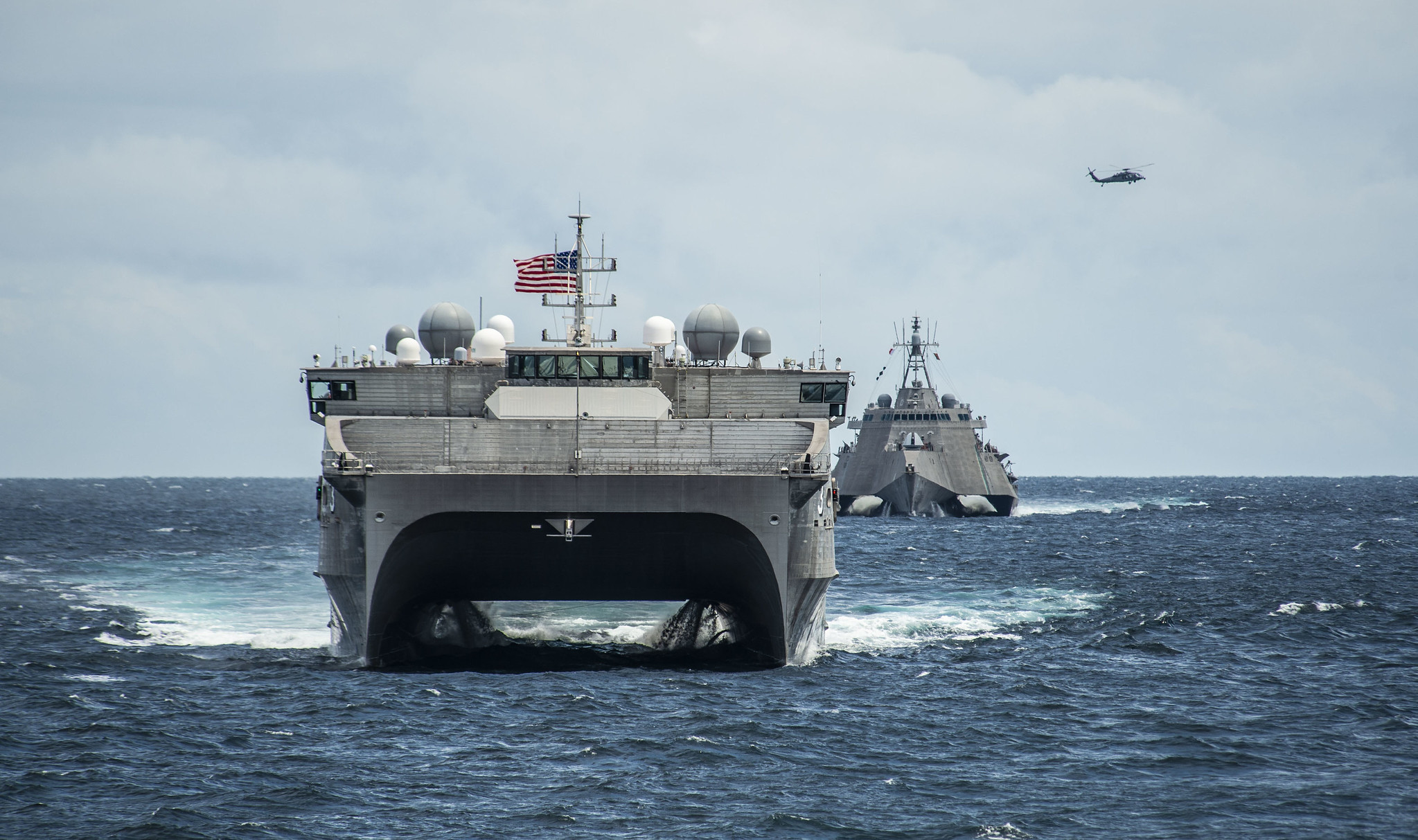 The Spearhead-class expeditionary fast transport ship USNS Millinocket (T-EPF 3), the Independence-variant littoral combat ship USS Montgomery (LCS 8) and an MH-60S Sea Hawk helicopter assigned to the Wildcards of Helicopter Sea Combat Squadron (HSC) 23 assemble in formation Oct. 29, 2019, for a photo exercise in support of Cooperation Afloat Readiness and Training (CARAT) Brunei. (Mass Communication Specialist 2nd Class Christopher A. Veloicaza/Navy)