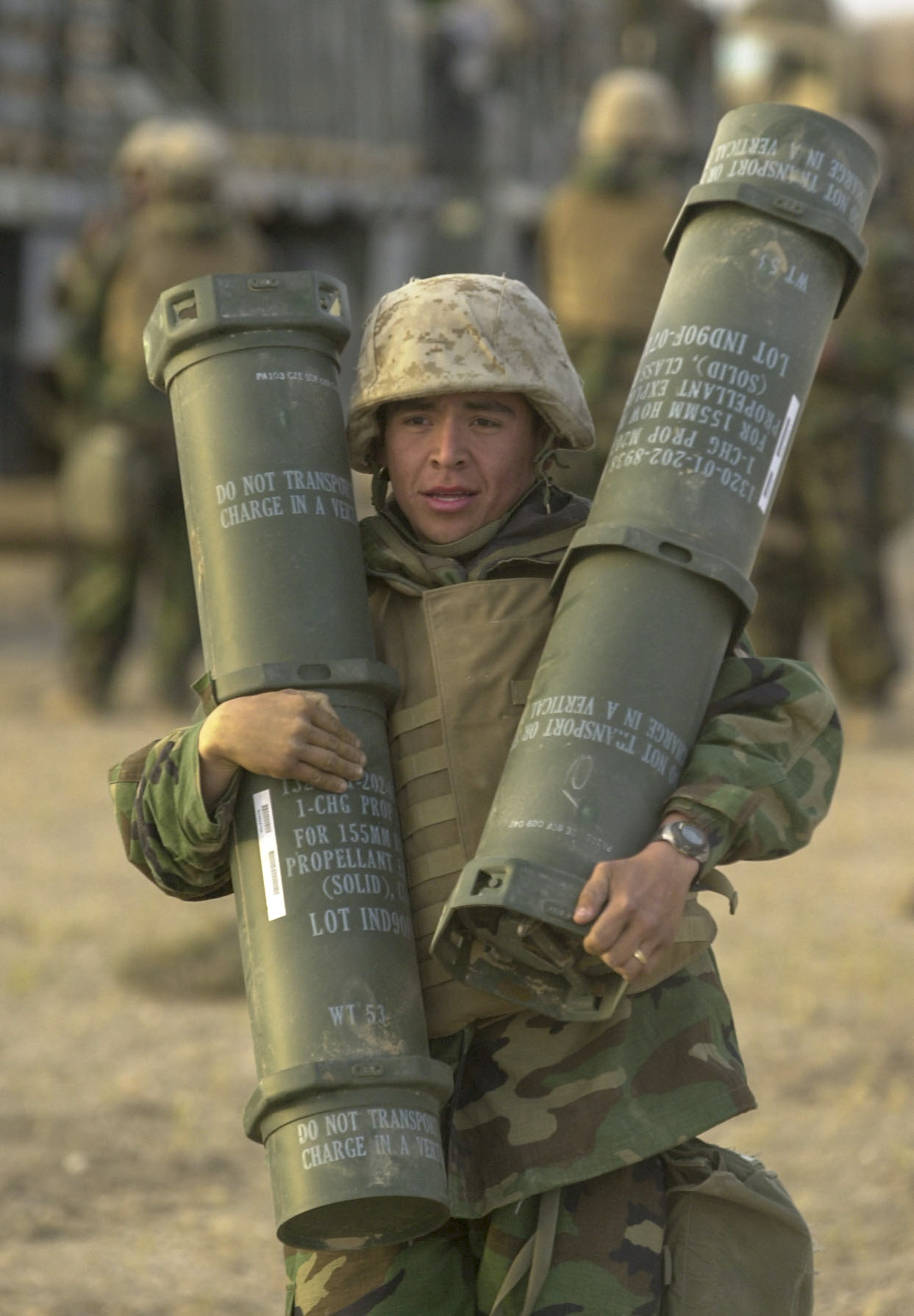 Lance Cpl. Steven Lopez, 19, with Battery M, 3rd Battalion, 11th Marine Regiment from Los Angeles, CA carries two charges for a 155mm howitzer during a ammunition resupply at an artillery position in southern Iraq on March 22, 2003. 03/22/2003 ( Jud McCrehin/Marine Corps Times)