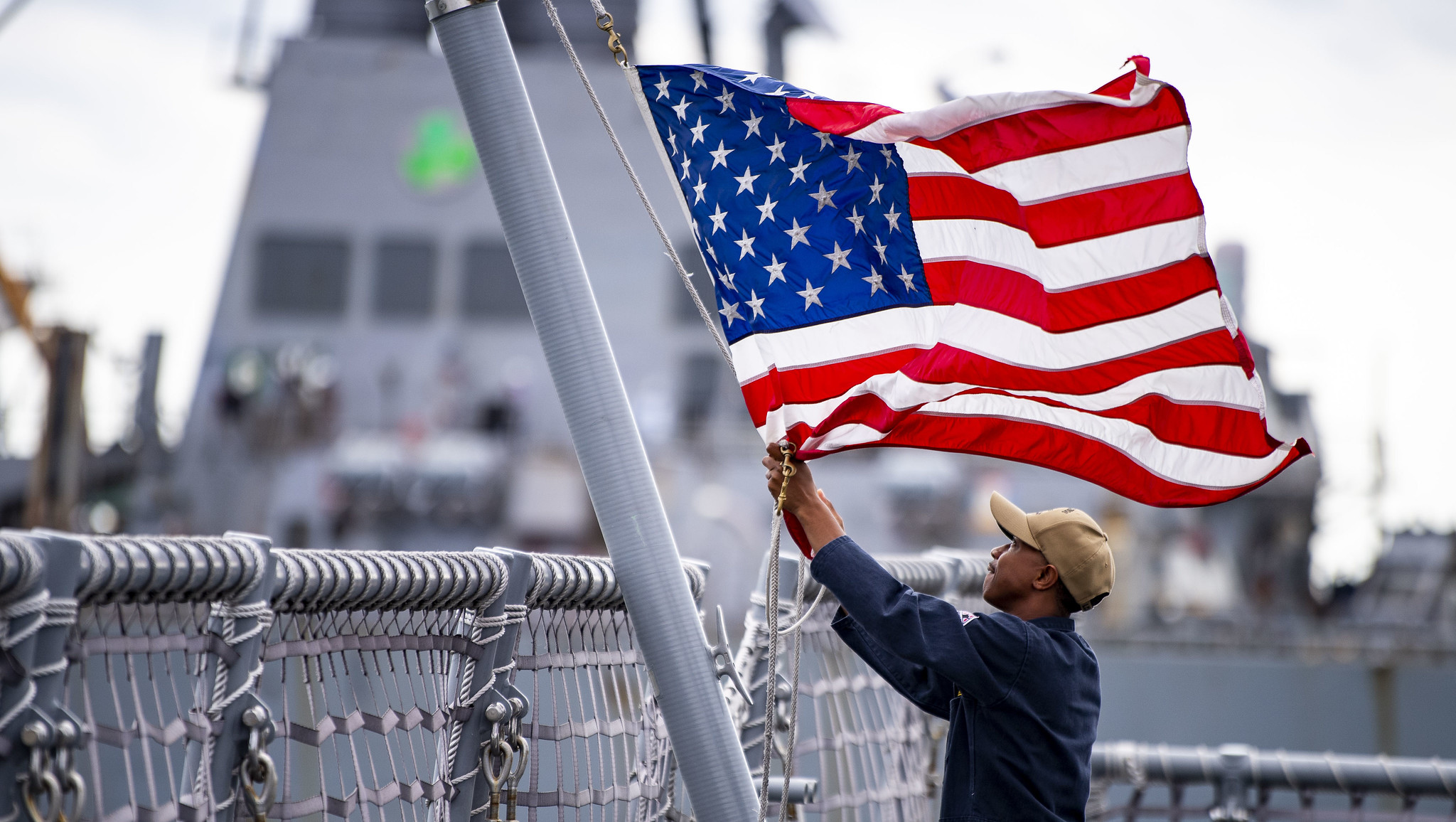 A sailor assigned to the Freedom-class variant littoral combat ship USS Billings (LCS 15) lowers the American flag Aug. 30, 2019, as the ship get underway from Naval Station Mayport. The commander of the U.S. 4th Fleet ordered all U.S. Navy ships homeported in the area to sortie ahead of Hurricane Dorian. (Mass Communication Specialist 3rd Class Nathan T. Beard/Navy)