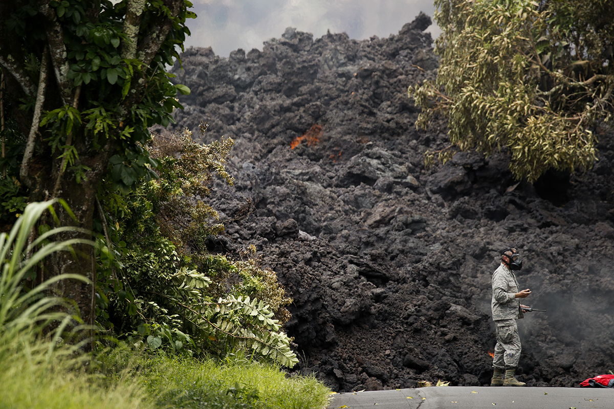 Air Force Lt. Col. Chuck Anthony wears a gas mask as he stands next to a wall of lava entering the ocean near Pahoa, Hawaii. White plumes of acid and extremely fine shards of glass billowed into the sky over Hawaii as molten rock from Kilauea volcano poured into the ocean, creating yet another hazard from an eruption that began more than two weeks ago: A toxic steam cloud. (AP Photo/Jae C. Hong, file)