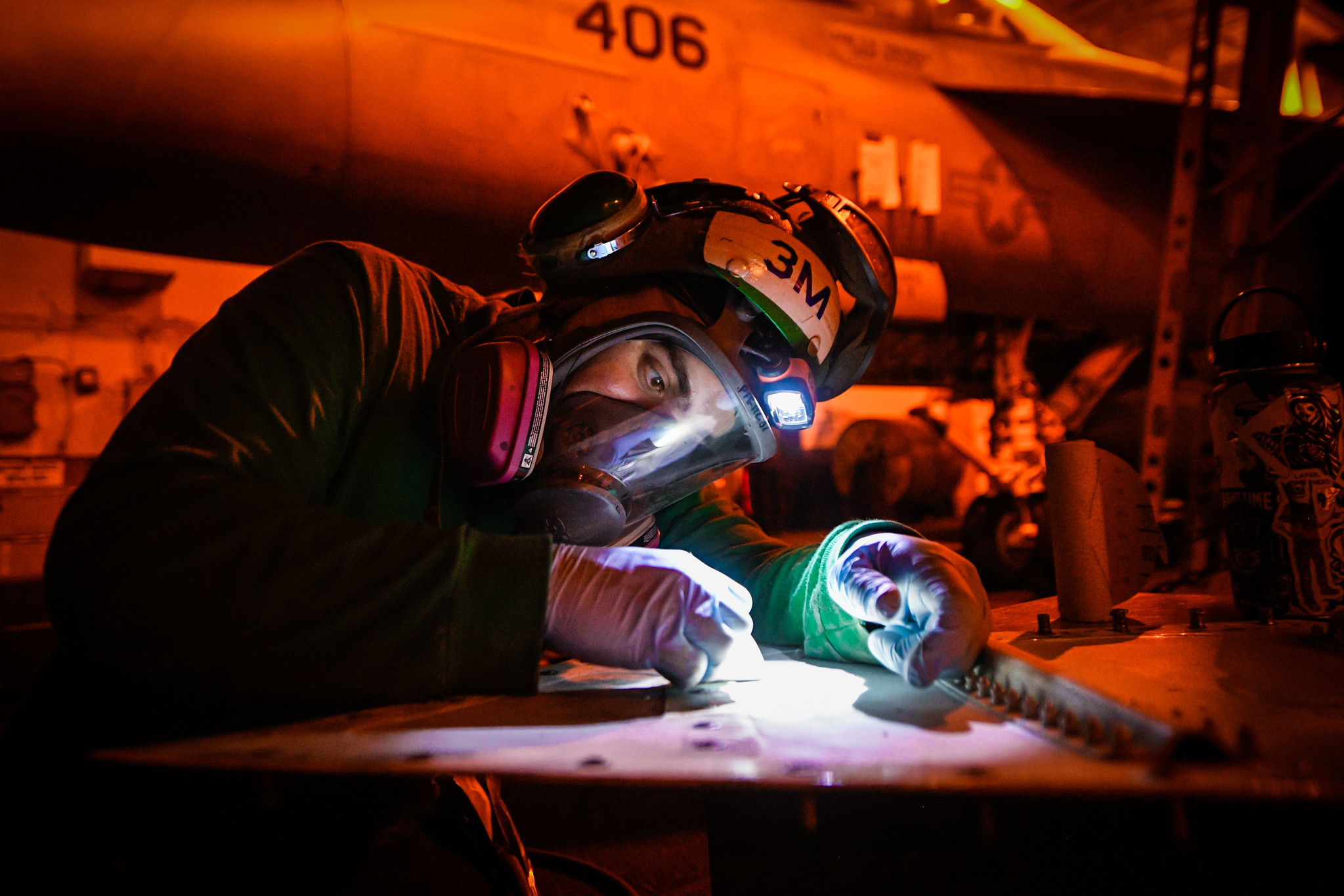 Aviation Structural Mechanic 3rd Class James Murray removes corrosion from a panel on an F/A-18E Super Hornet on March 2, 2020, in the hangar bay of the aircraft carrier Theodore Roosevelt (CVN 71) in the Pacific Ocean. (Mass Communication Specialist Seaman Olympia O. McCoy/Navy(