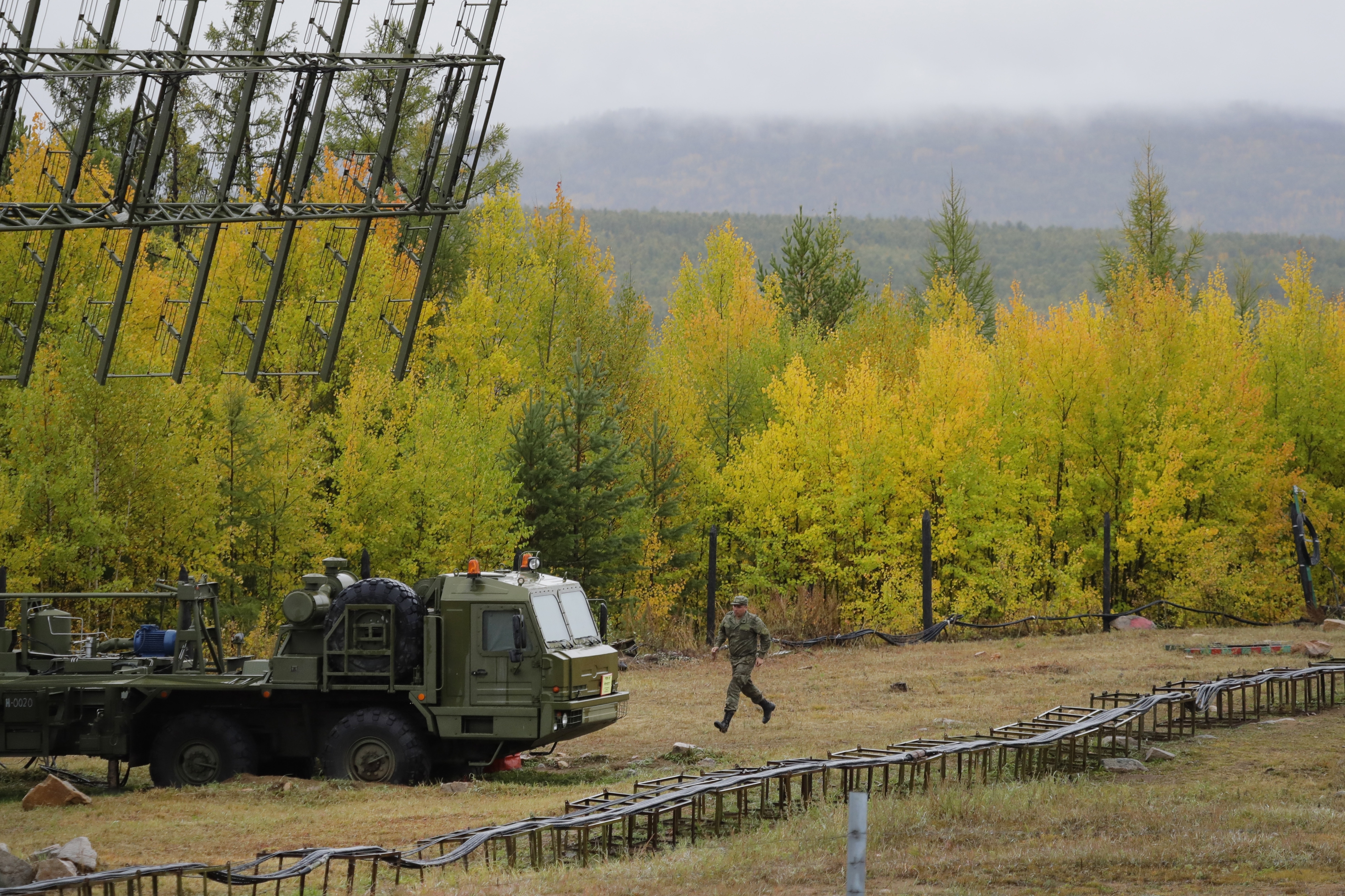 A Russian soldier runs towards a Nebo-M radar deployed by a forest, during a military exercises on training ground 