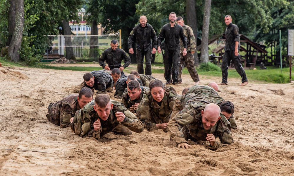 Soldiers from 278th Armored Cavalry Regiment along with Polish soldiers low crawl in the sand during day two of training for the water survival course hosted by 15th Mechanized Brigade in Gizycko, Poland, Aug. 12, 2019. (Tennessee National Guard)