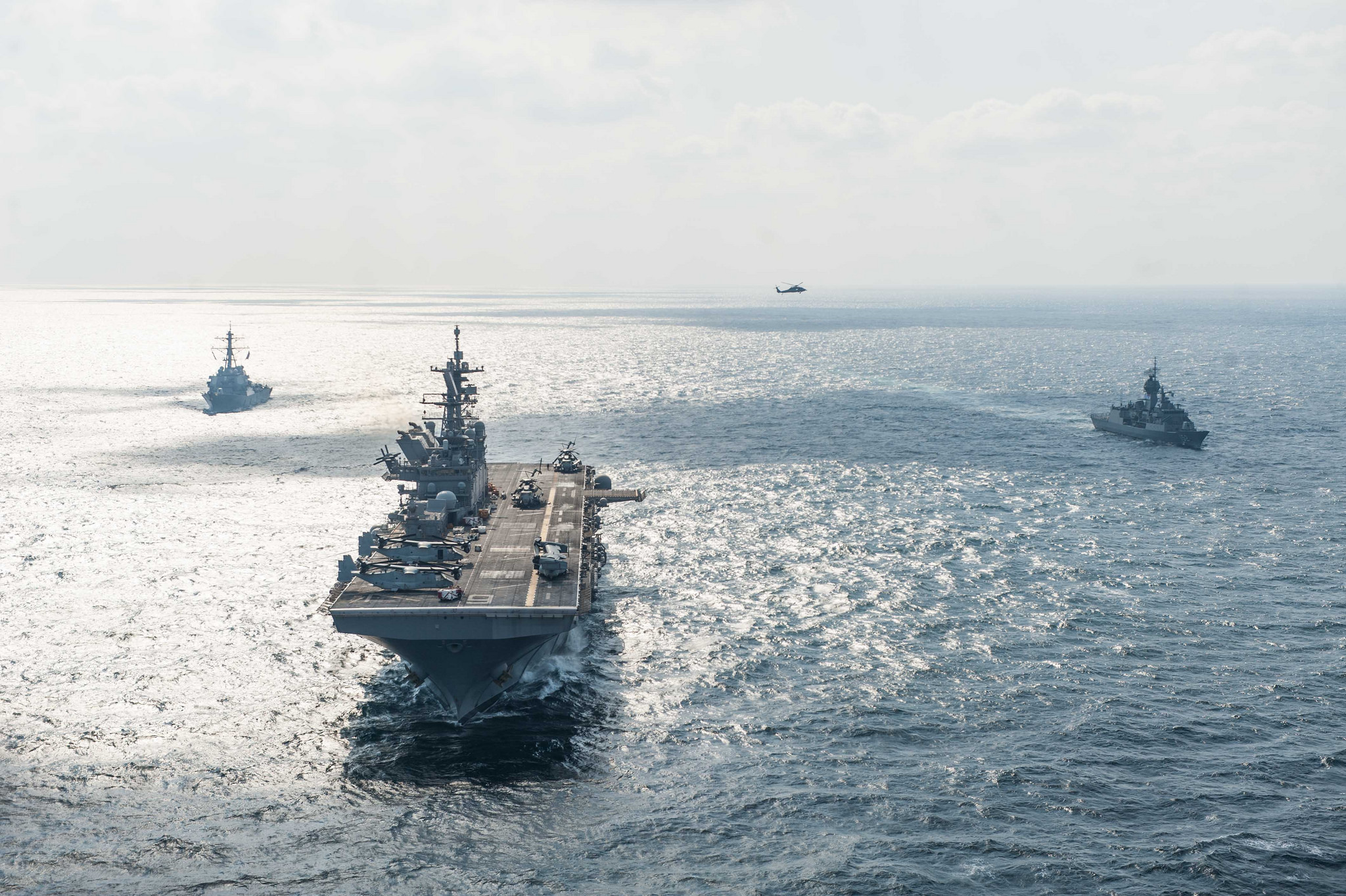 The amphibious assault ship USS America (LHA 6), center, the Arleigh Burke-class guided-missile destroyer USS Hopper (DDG 70), left, and the Anzac-class frigate HMAS Warramunga (FFH 152) steam in formation Nov. 28, 2017, while participating in a photo exercise in the Arabian Gulf. (MC2 Alexander Ventura II/Navy)