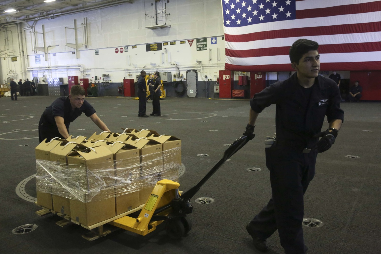 Sailors aboard the Nimitz-Class aircraft carrier USS Abraham Lincoln (CVN 72) move pallets of water on Sept. 11, 2017, in preparation to support those affected by Hurricane Irma. (Aviation Boatswain’s Mate (Equipment) 2nd Class Lauren D. Smith/Navy)