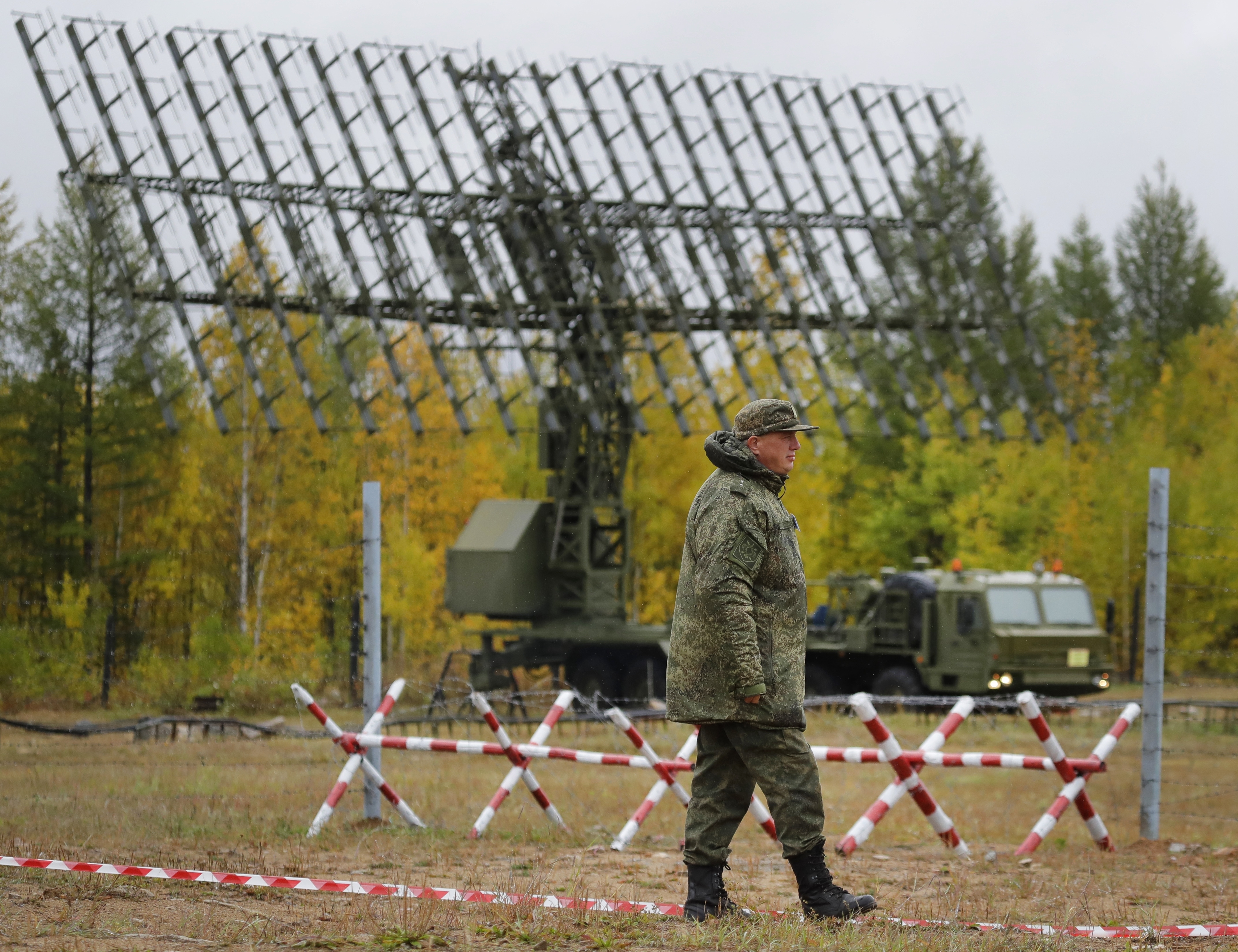 A Russian walks past a Nebo-M radar deployed in a forest, during a military exercises on training ground 