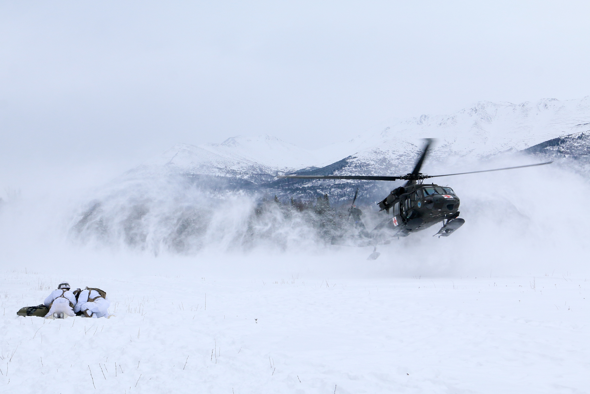 Paratroopers with U.S. Army Alaska huddle over a mock casualty to protect it from the rotor-wash of a landing UH-60 helicopter at Joint Base Elmendorf-Richardson, Alaska, Feb. 20, 2019. (Sgt. Alex Skripnichuk/Army)