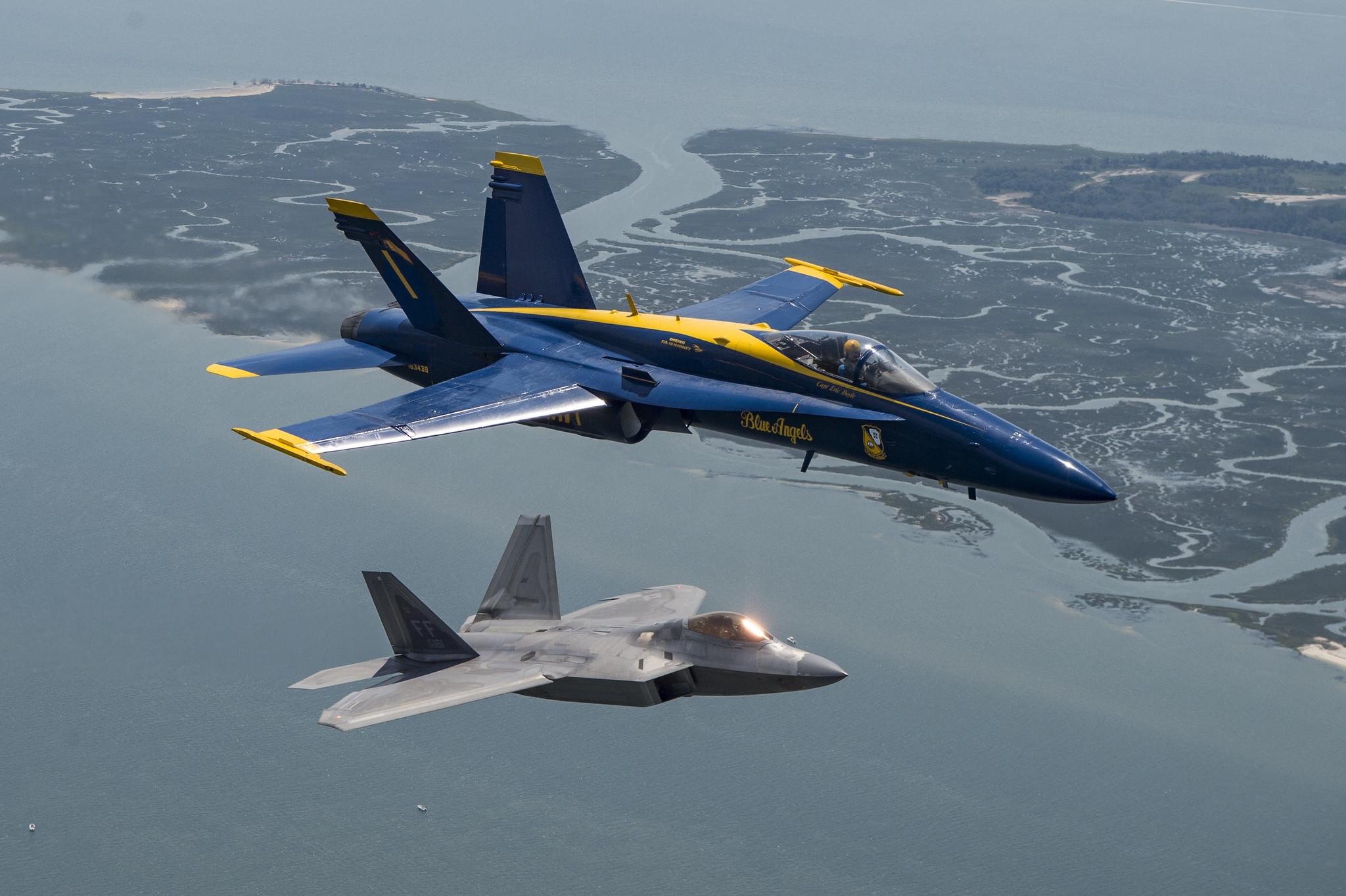 Capt. Eric Doyle, commanding officer of the U.S. Navy flight demonstration squadron, the Blue Angels, flies in formation with an F-22 Raptor assigned to the U.S. Air Forces F-22 Raptor demonstration team April 25, 2019, during a photo exercise above Marine Corps Air Station Beaufort. (Mass Communication Specialist 2nd Class Christopher Gordon/Navy)