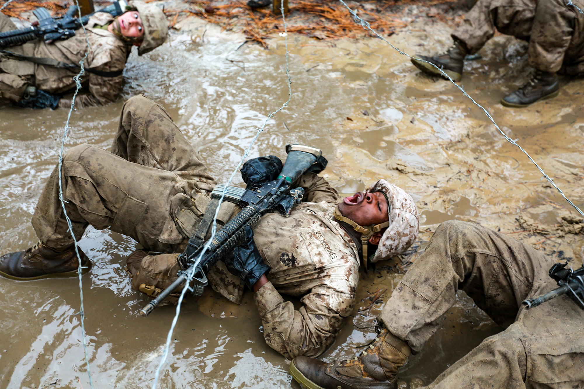 Recruits with Delta Company, 1st Recruit Training Battalion maneuver through mud and barbed wire during the Combat Endurance Course on Dec. 21, 2019, at Marine Corps Recruit Depot Parris Island, S.C. (Gunnery Sgt. Tyler Hlavac/Marine Corps)