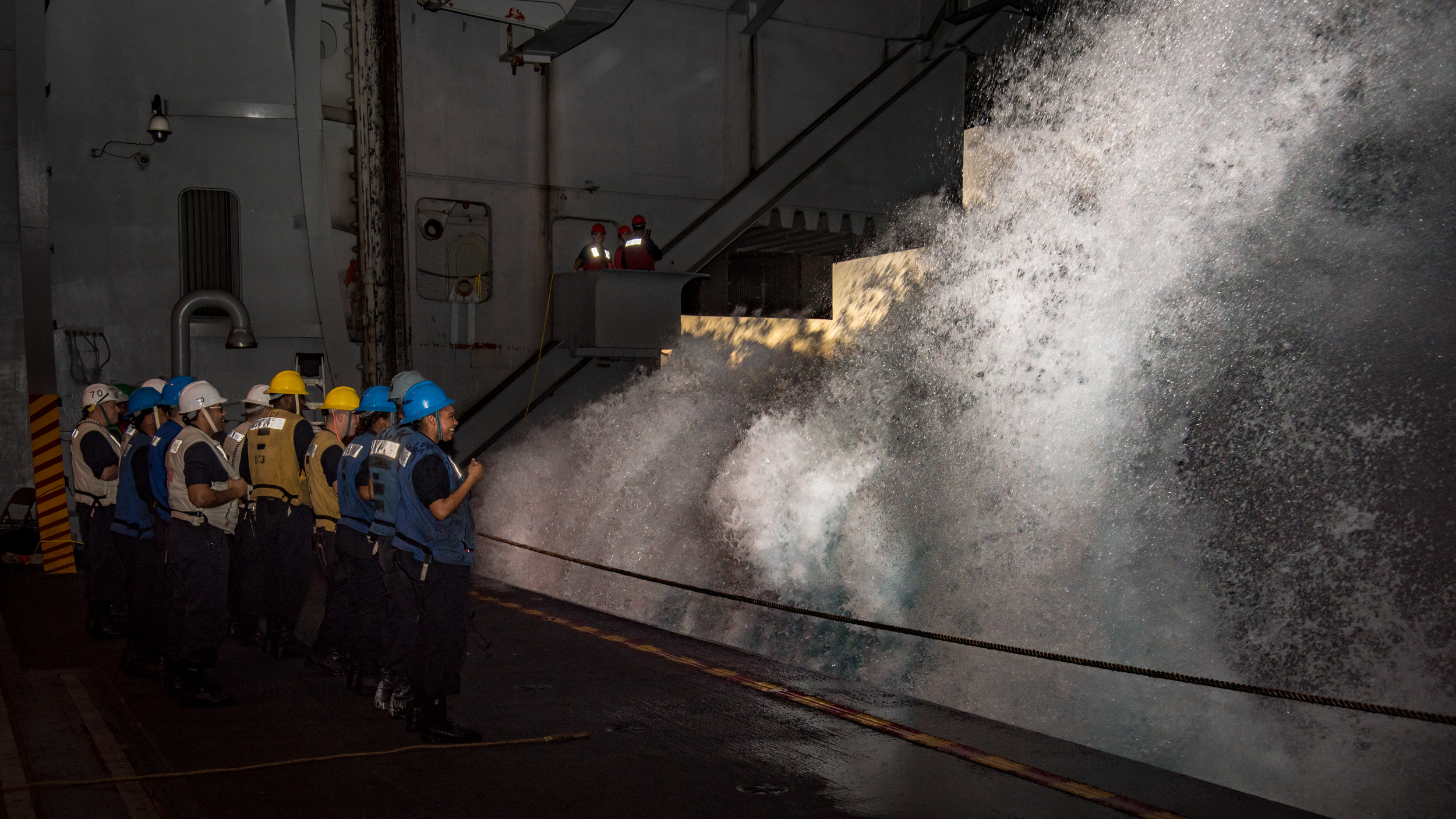 Sailors aboard Nimitz-class aircraft carrier USS Carl Vinson (CVN 70) watch as a wave crashes into the hangar bay during a replenishment-at-sea with Fleet Replenishment Oiler USNS Yukon (T-AO 202). U.S. Navy Photo by Mass Communication Specialist 3rd Class Kurtis A. Hatcher