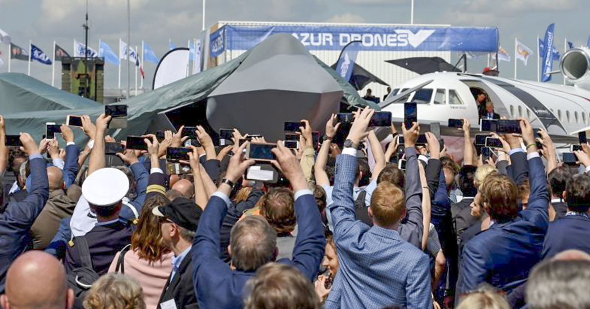 Visitors attend the unveiling ceremony of the full-scale jet fighter model of the the Franco-German-Spanish Future Combat Air System at the Paris Air Show on June 17, 2019. (Eric Piermont/AFP via Getty Images)