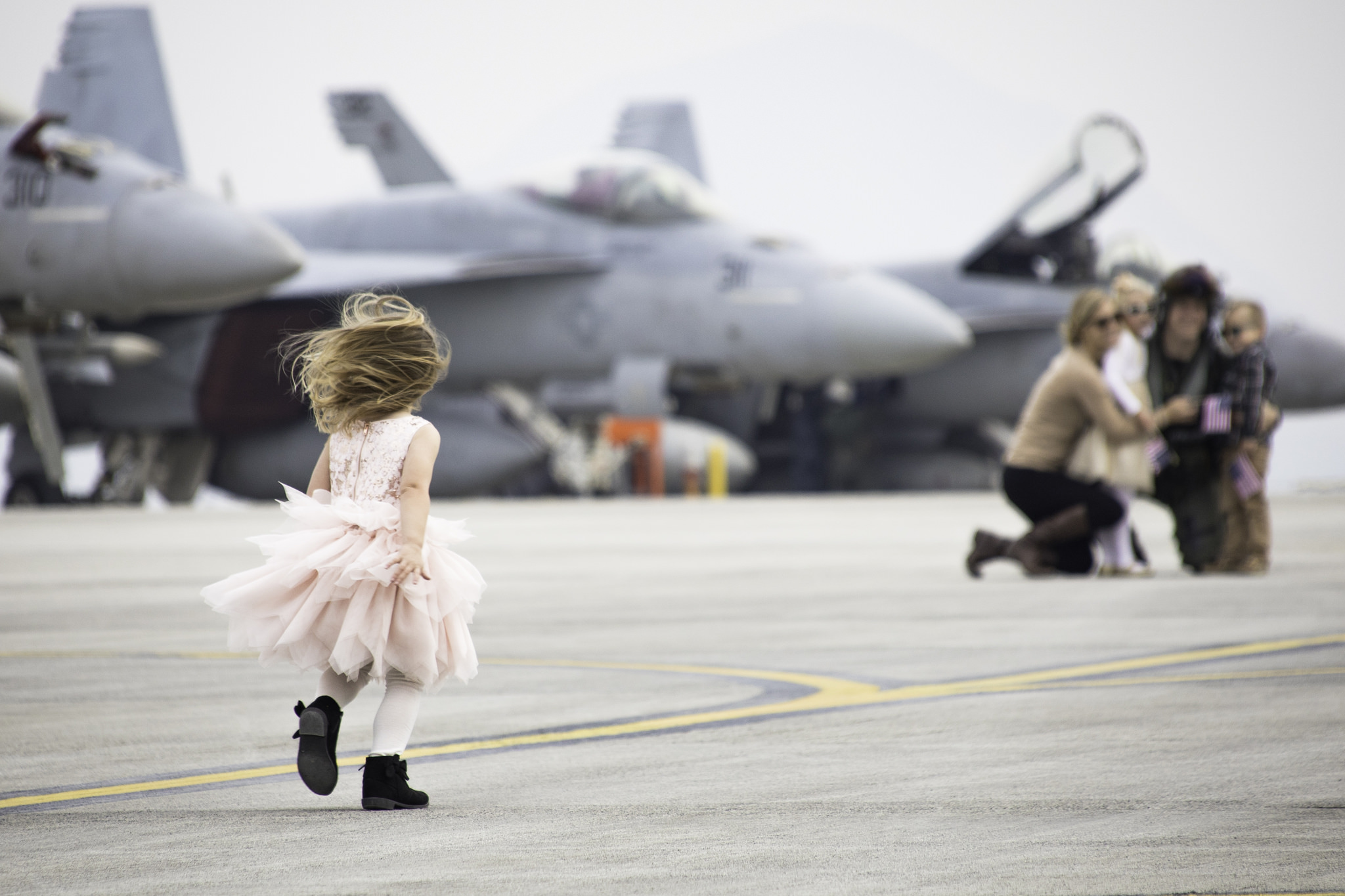 A young girl runs to greet her family after the arrival of Strike Fighter Squadron (VFA) 115, VFA-195 and Electronic Attack Squadron (VAQ) 141 at Marine Corps Air Station (MCAS) Iwakuni, Japan. VFA-115, VFA-195 and VAQ 141 arrived at MCAS Iwakuni as part Carrier Air Wing (CVW) 5’s relocation from Naval Air Facility (NAF) Atsugi, Japan. (Cpl. Joseph Abrego/Marine Corps)