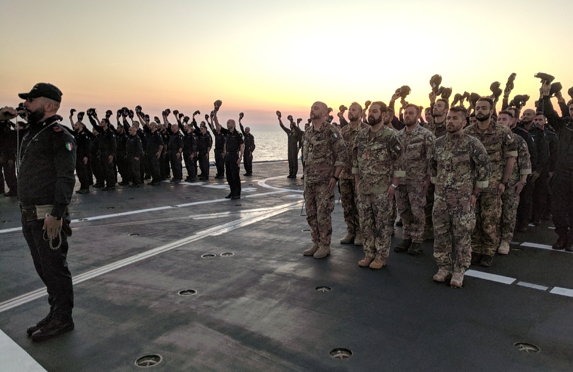 The crew and embarked Marines onboard the Italian FREMM Alpino participate in a weekly evening colors ceremony on the flight deck. (David B. Larter/Staff)