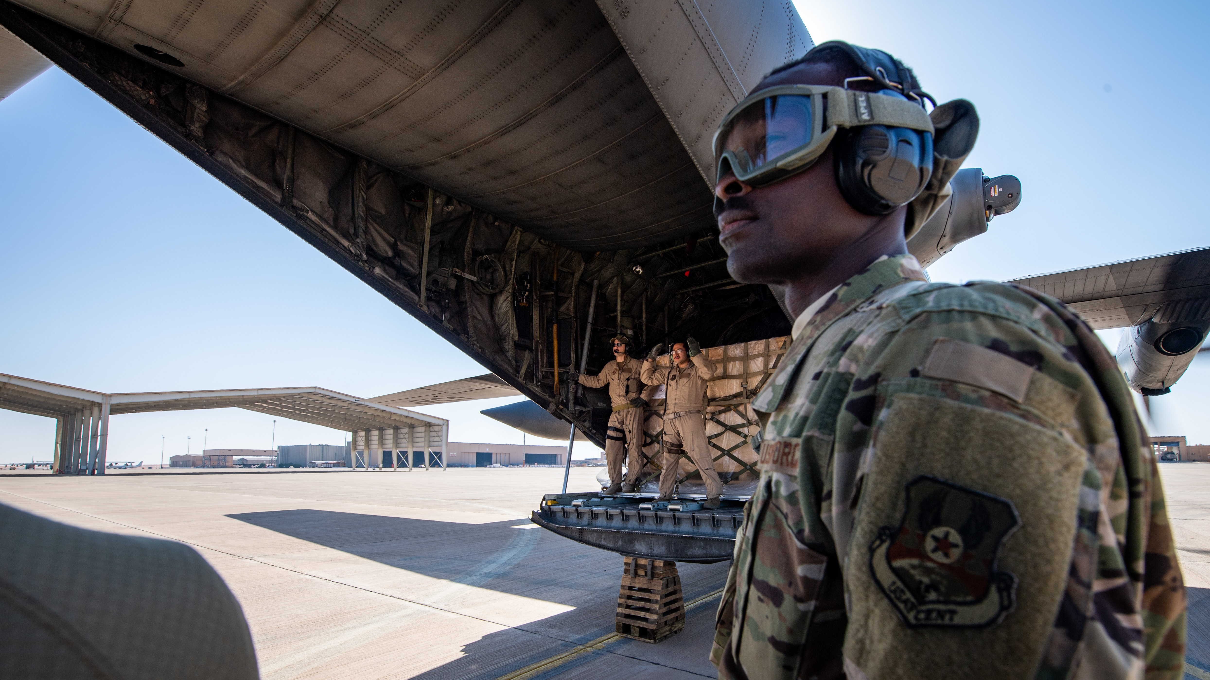 C-130 Hercules loadmasters and aerial porters stand-by as a K-loader moves into position to unload cargo at Prince Sultan Air Base, Saudi Arabia, Dec. 24, 2019. (Tech. Sgt. Michael Mason/Air Force)