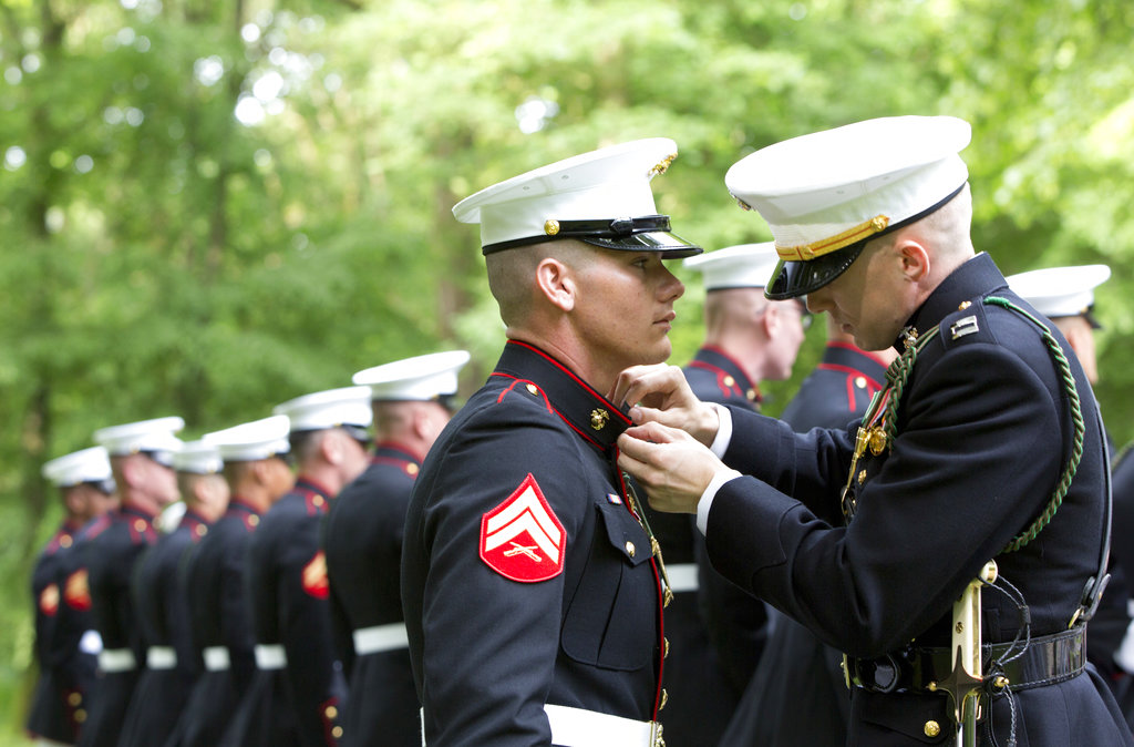 A U.S. Marine Corps officer, right, helps an enlisted Marine adjust his tunic as they participate in a commemoration at the American Marine Memorial in Belleau Wood prior to a service at the Aisne-Marne American Cemetery in Belleau, France, Sunday, May 27, 2018. (Virginia Mayo/AP)