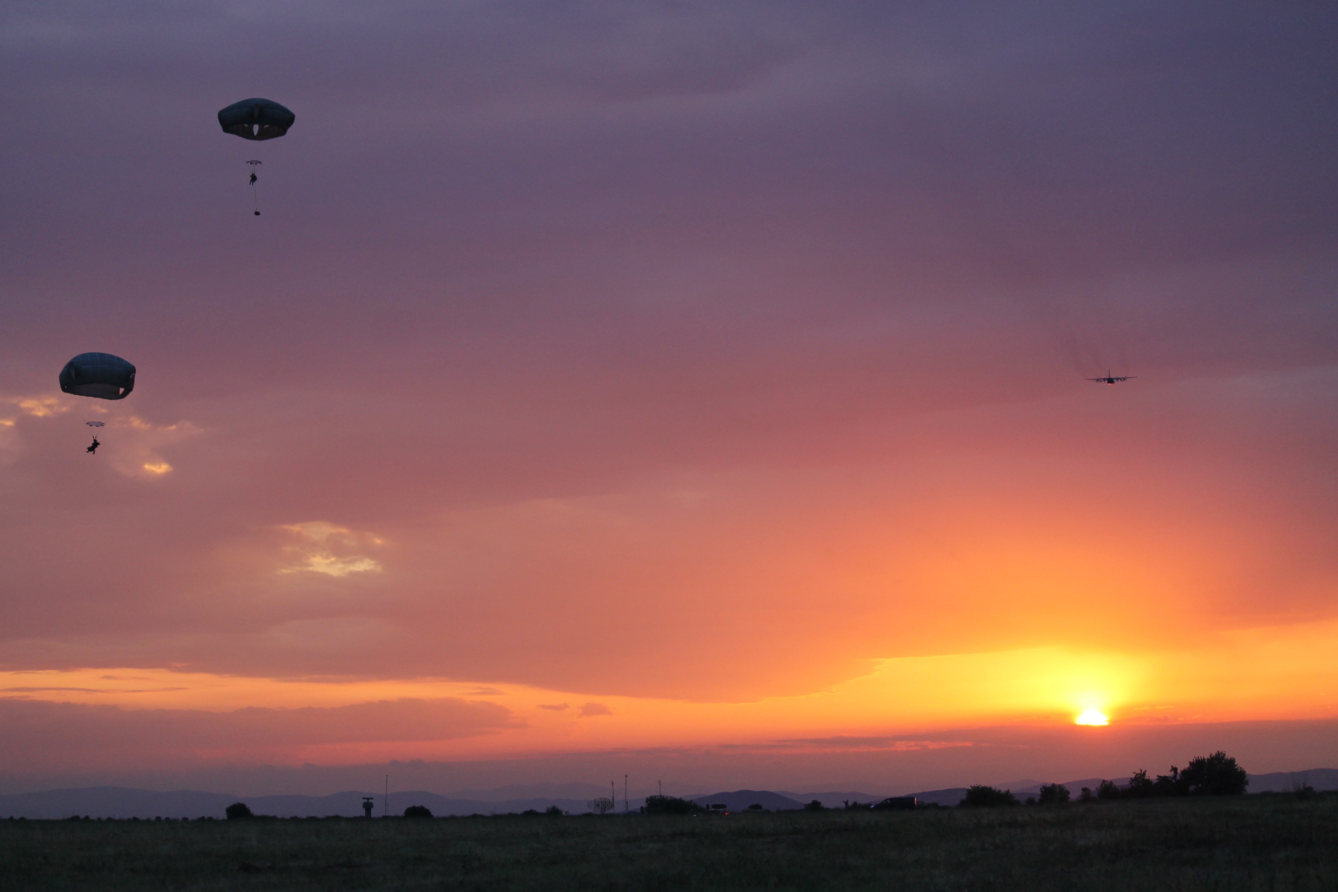 The last of the paratroopers land as a C-130 flies off into the sunset. While there were a dozen injuries that required temporary hospitalization as the result of a jump in Romania, also part of the Saber Guardian exercise, the Bezmer jump had minimal injuries. (Jen Judson/Staff)