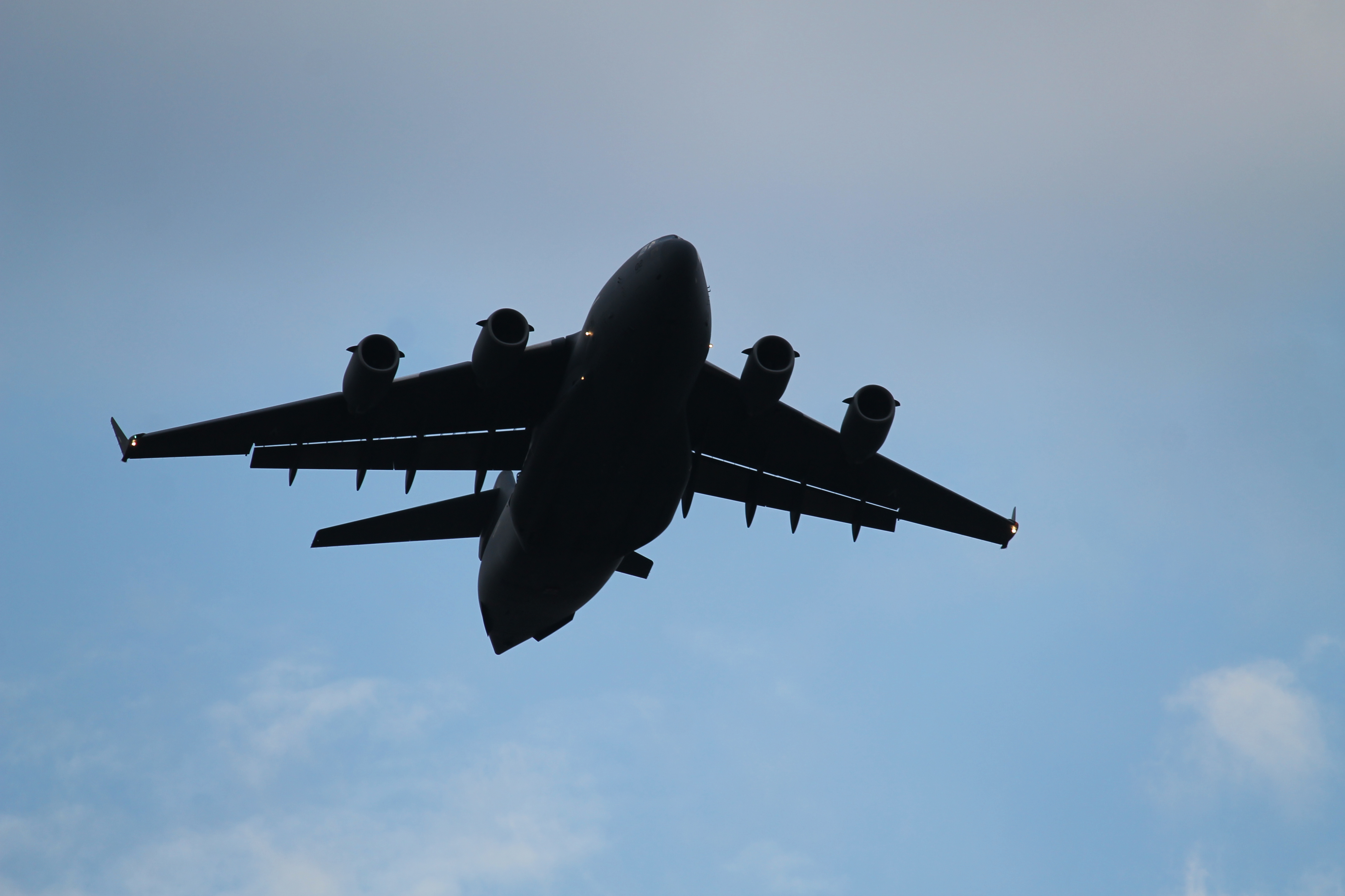 A C-17 flies over a drop zone at Bezmer Air Base, Bulgaria, at dusk on July 18. Eleven C-130s and two C-17s passed over the airfield, dropping paratroopers from the 173rd Airborne Brigade Combat Team based out of Vicenza, Italy, along with others from Portugal and Canada as part of Swift Response, an exercise within Saber Guardian. (Jed Judson/Staff)